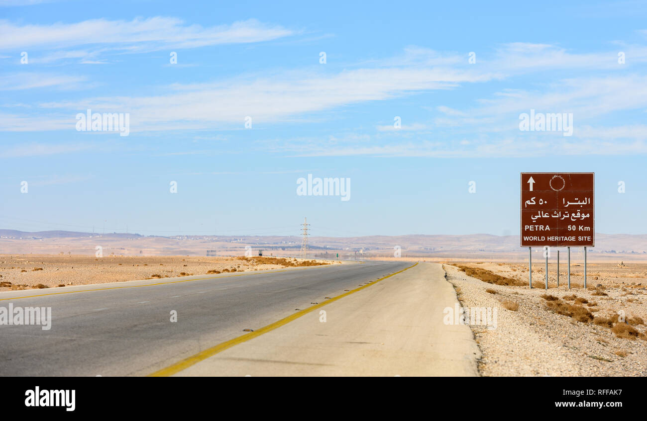 Kings Highway, belle route sinueuse qui traverse le désert de Wadi Rum avec un panneau routier indiquant la distance pour atteindre Pétra, en Jordanie. Banque D'Images