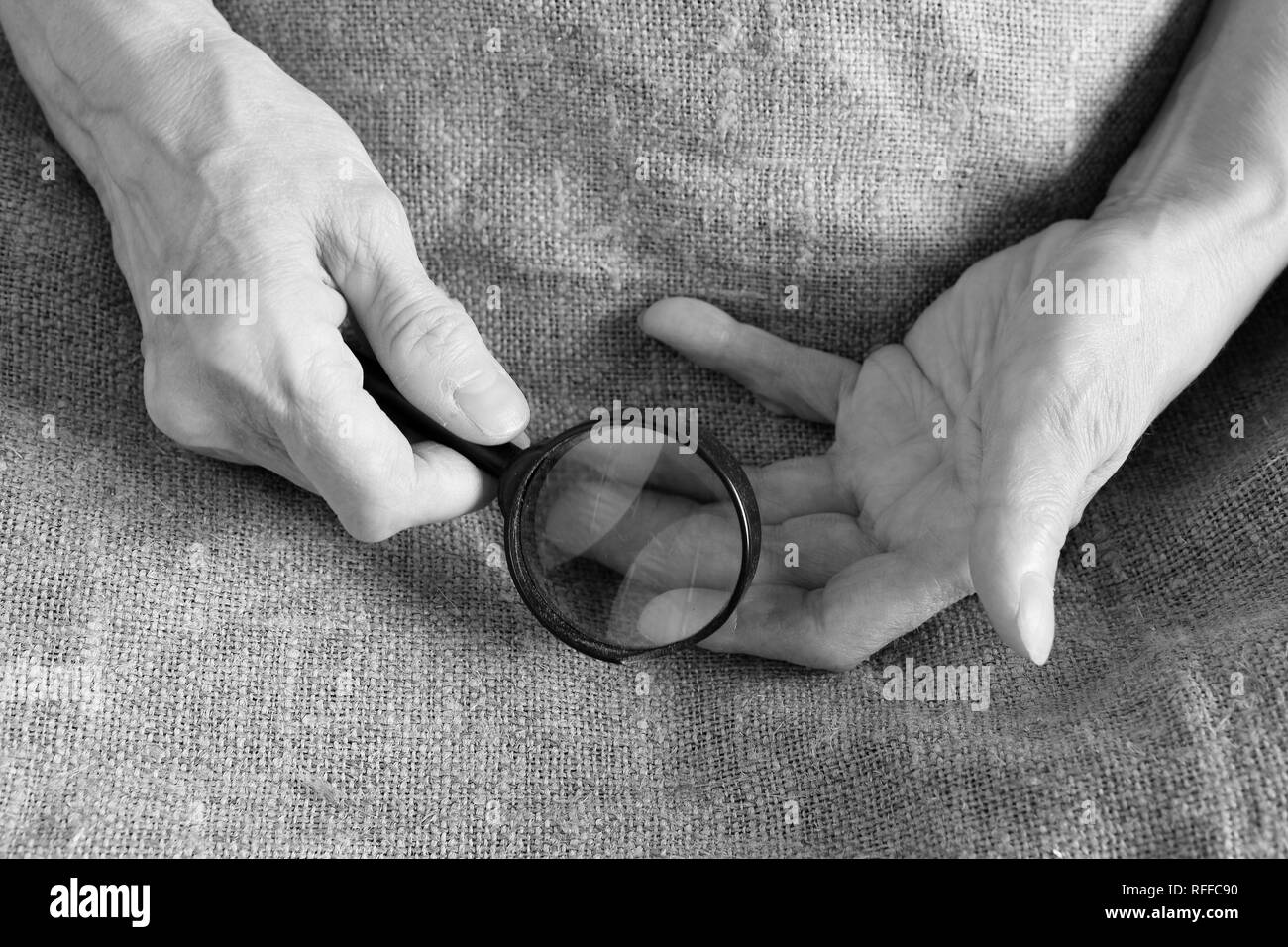 Mains d'une vieille femme tenant une loupe. Close-up. Banque D'Images