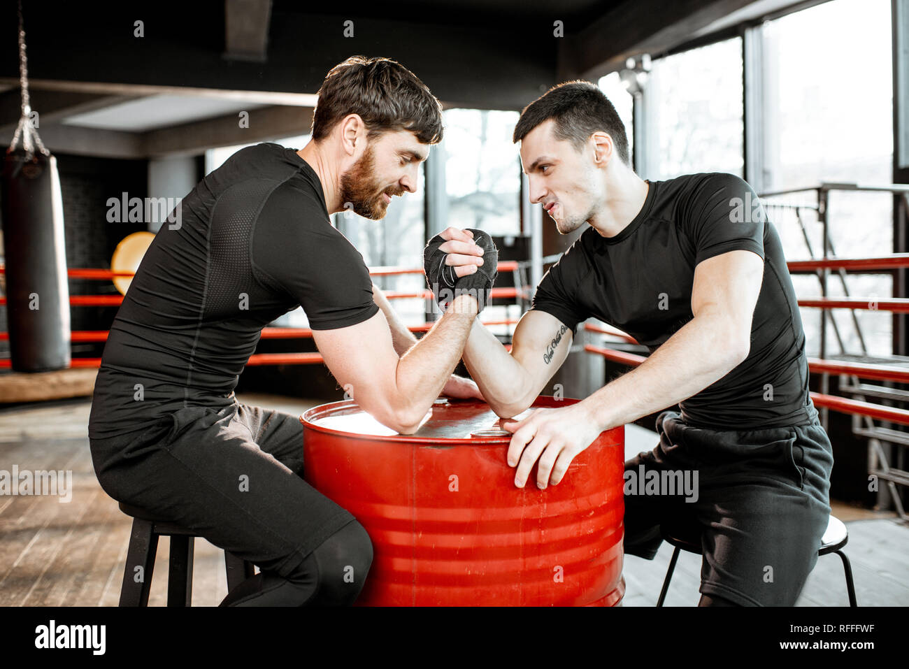 Deux jeunes athlètes en noir sportswear ayant un bras de fer dur la ...