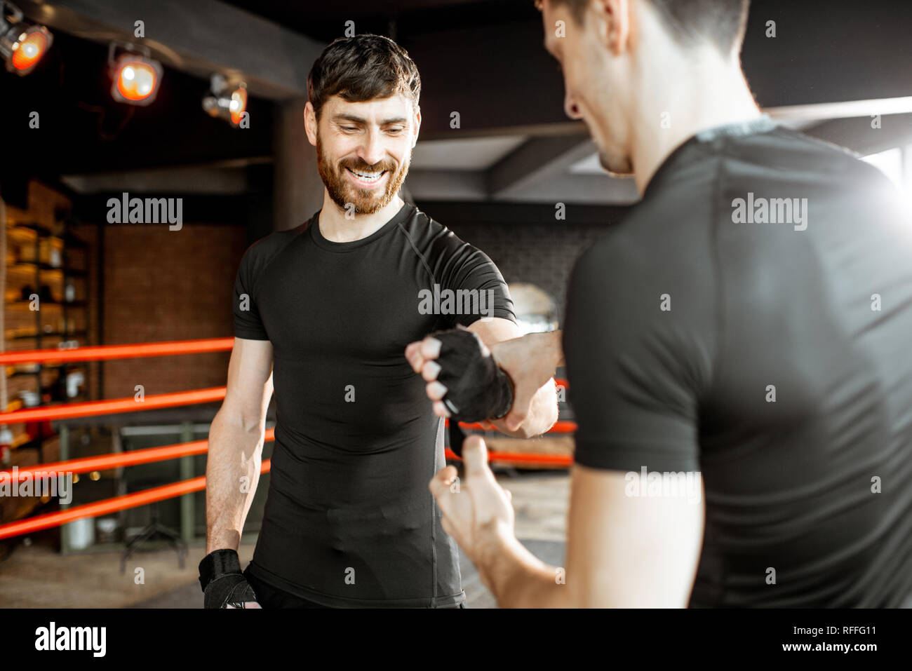 Bobinage formateur bandage sur le poignet d'un beau barbu, la préparation de la boxe sur le ring de boxe à la salle de sport Banque D'Images
