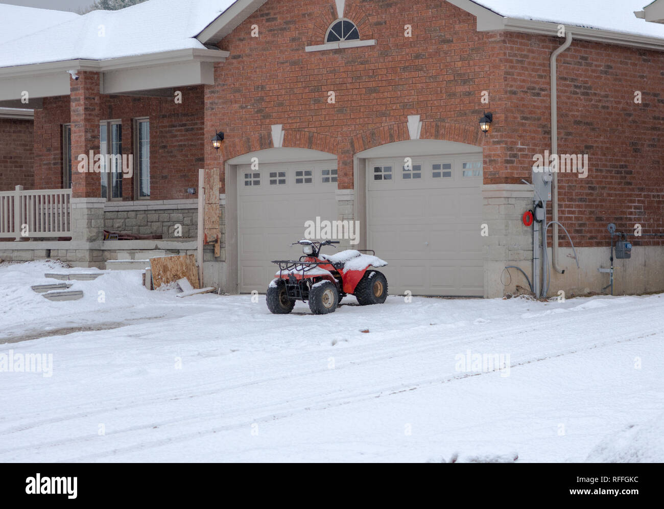 La première neige est tombée et a couvert la cour et l'ATV à gauche près du garage Banque D'Images