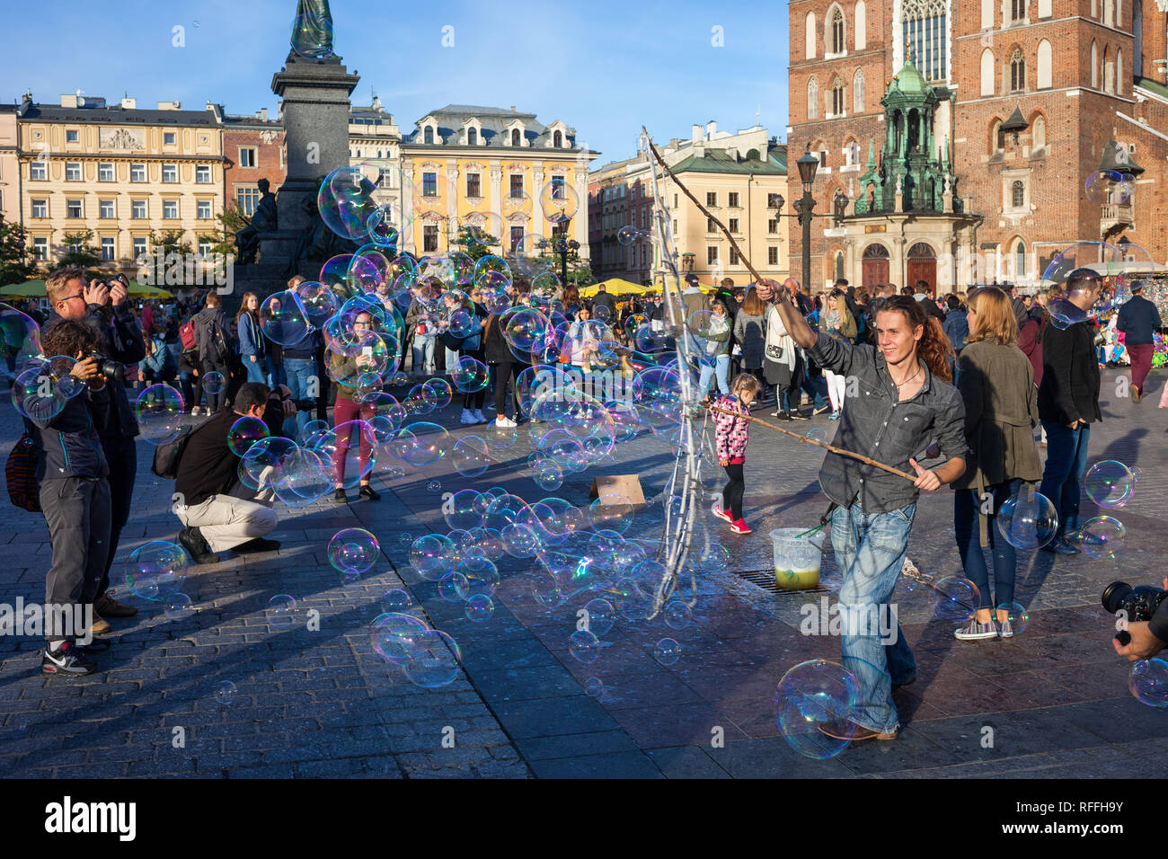 La Pologne, la ville de Cracovie, les gens, les enfants, les touristes regardant jeune homme faisant des bulles de savon sur la place principale de la vieille ville animée Banque D'Images