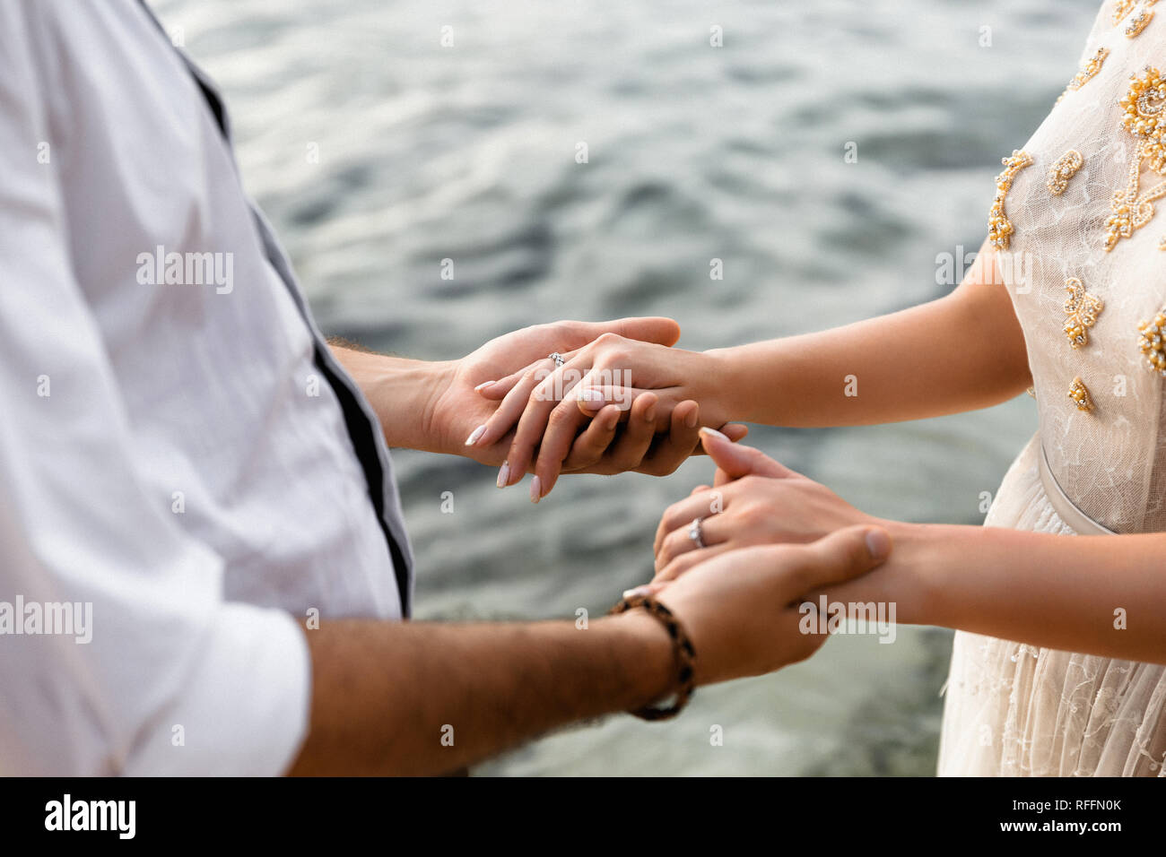 Un jeune homme tient dans ses mains les mains d'une fille à l'arrière-plan d'eau, photo gros plan Banque D'Images