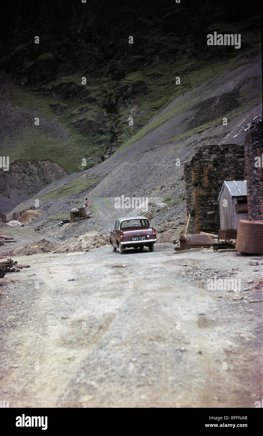 Années 1960, historique, 2 portes Ford Anglia voiture garée sur le gravier à la demeure d'une ancienne mine de cuivre ou de métal, Braithwaite, Lake District, Cumbria, England, UK Banque D'Images