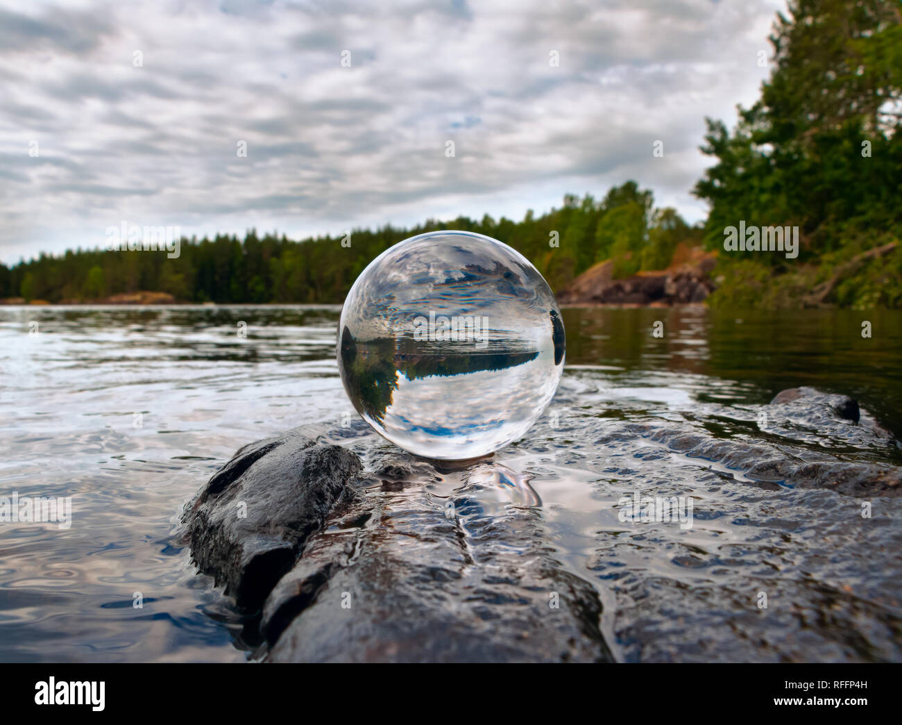 Boule de cristal acrylique sur roche par un lac Banque D'Images