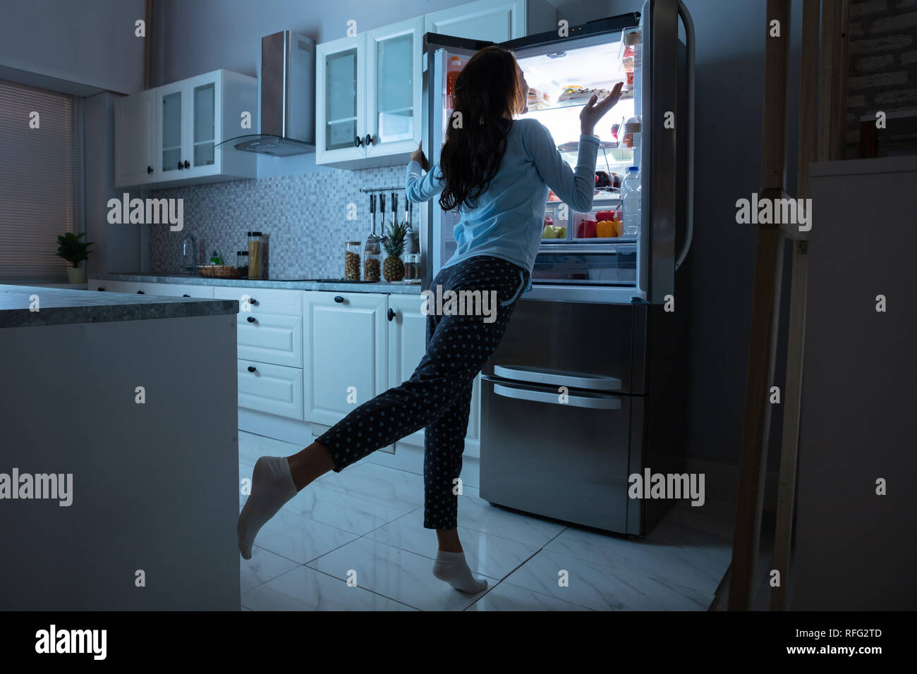 L'ouverture de porte du réfrigérateur femme avec divers aliments dans la cuisine Banque D'Images