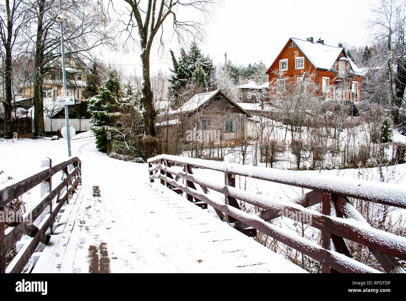 Pont de bois en hiver, les arbres et les maisons en bois et recouvert de neige dans un village Banque D'Images