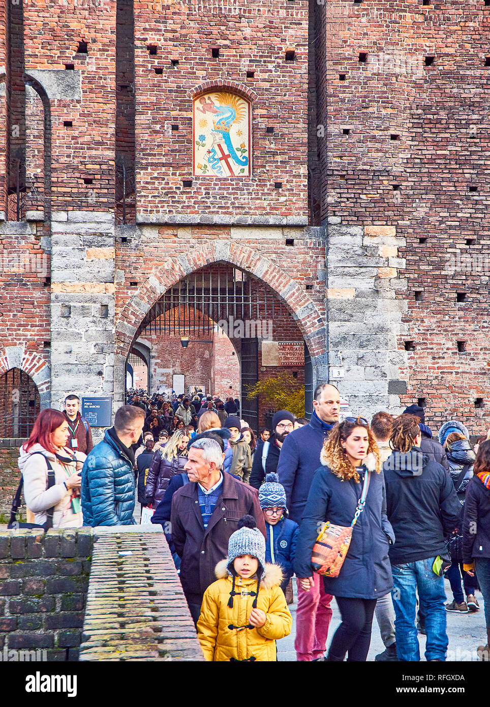 Touristes traversant l'une des portes de la Villa Reale, le château des Sforza, avec le Blason des Visconti sur l'arche. Milan, Lombardie, Italie. Banque D'Images