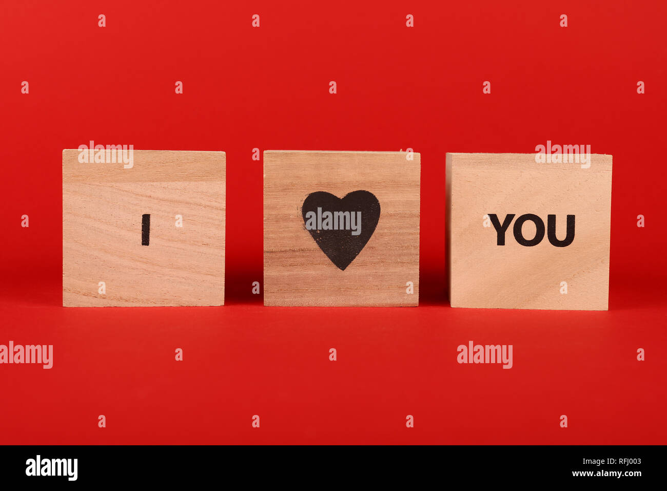 Cube de bois signe avec JE VOUS AIME paroles sur fond rouge et l'espace de copie, low angle view Banque D'Images