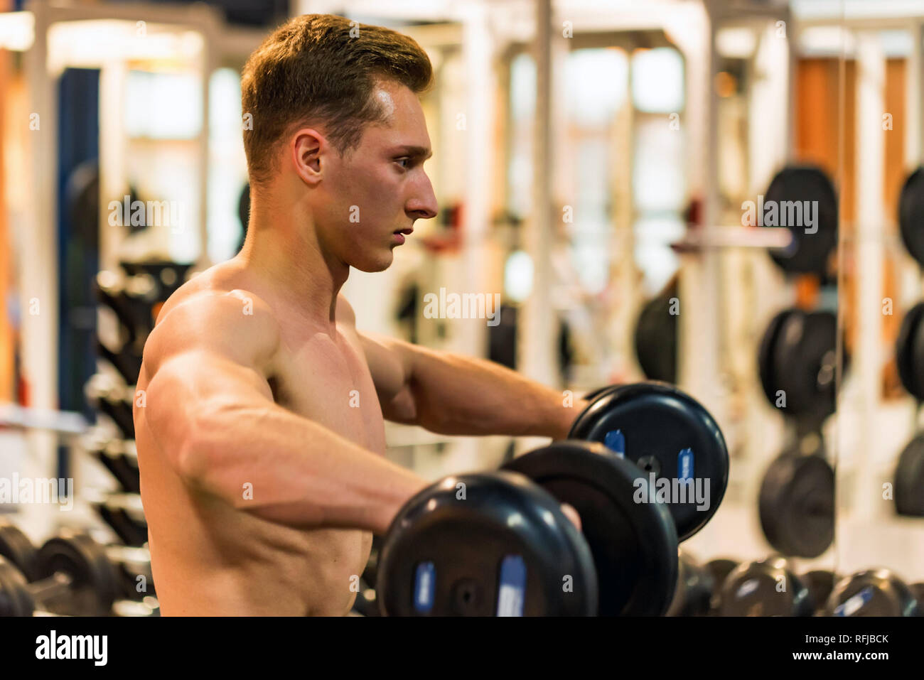 Athlète masculin attrayant faisant de l'exercice avec haltères biceps Banque D'Images