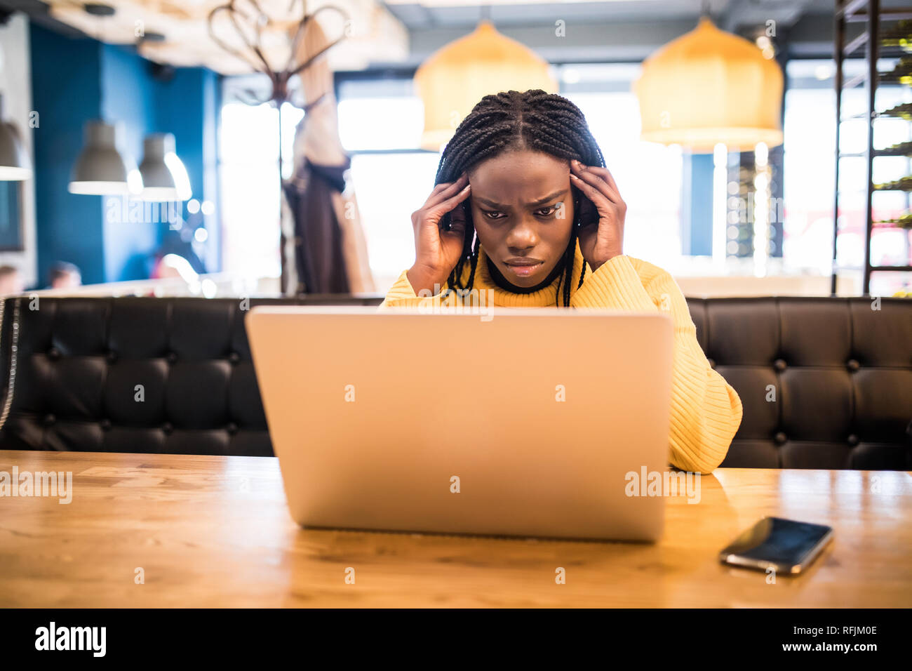 Jeune femme africaine avec coffre souffrance de maux de tête alors qu'il était assis dans le café Banque D'Images