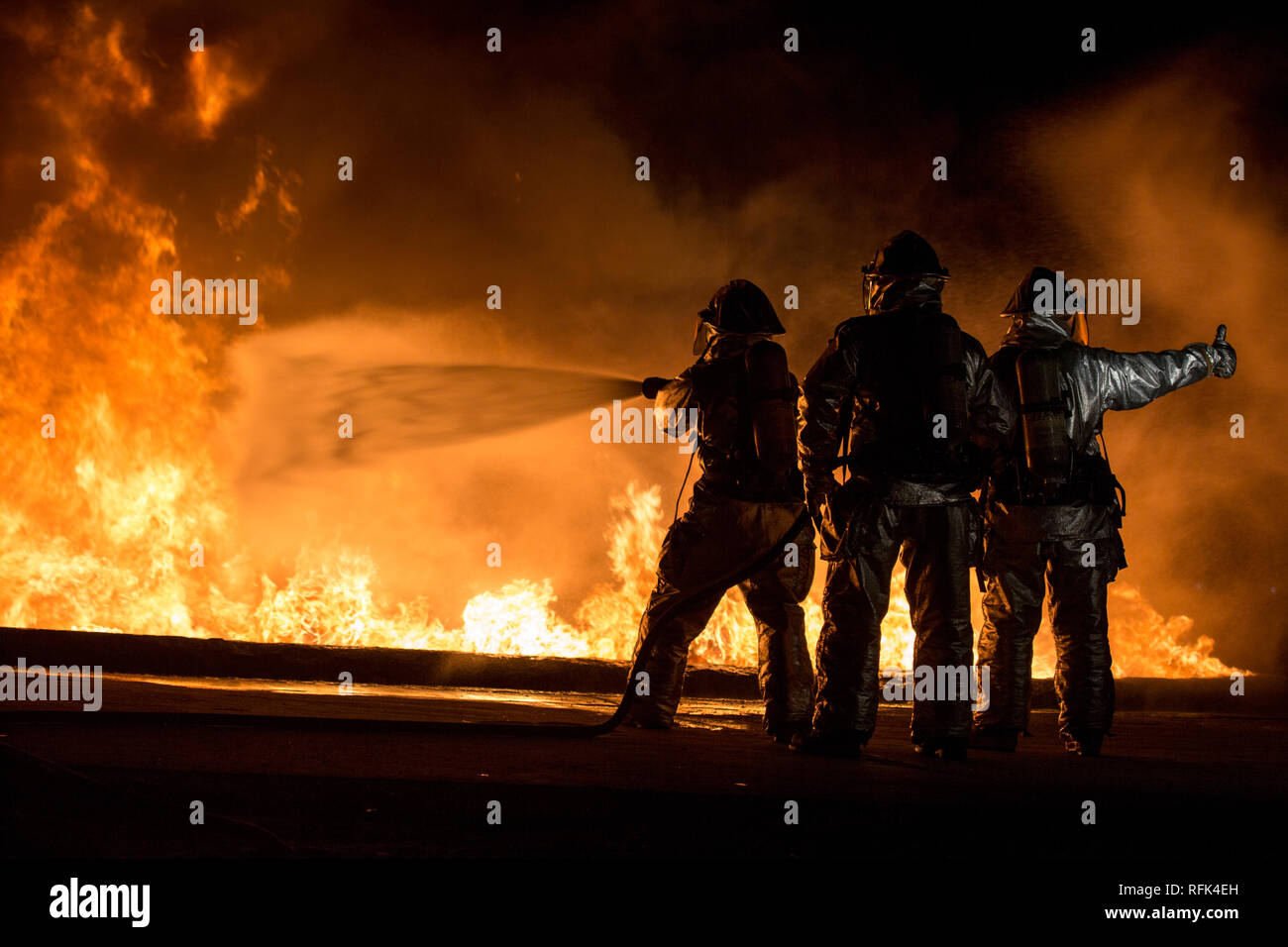 Avec les Marines américains de sauvetage et de lutte contre les incendies d'aéronefs (SLIA) utiliser une ligne d'éteindre un incendie de carburant le 24 janvier 2019 au cours de vivre-burn sur formation Futenma Marine Corps Air Station, Okinawa, Japon. La formation est organisée chaque mois pour fournir des services SLIA Marines avec des scénarios de formation pour accroître leur capacité de réagir à tout danger ou d'urgence sur la ligne de vol. L'entrée des Marines SLIA zone d'entraînement et utilisé différentes lignes à main, aussi connu sous un tuyau d'incendie, de maîtriser et d'éteindre l'incendie. (U.S. Marine Corps photo par Lance Cpl. Nicole Rogge) Banque D'Images