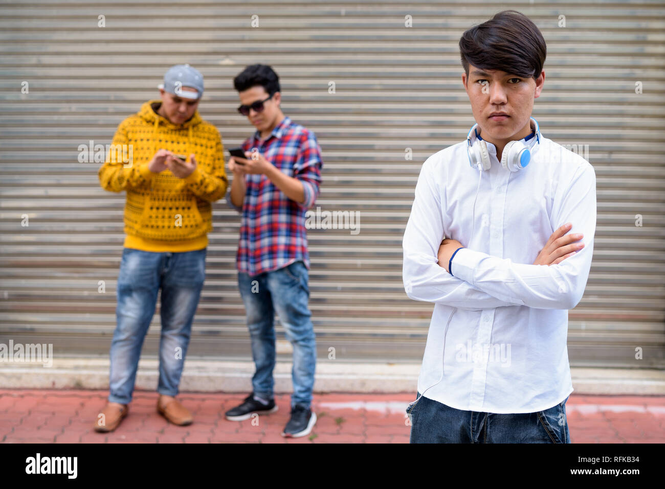 Trois jeunes hommes asiatiques contre la porte de l'entrepôt dans le str Banque D'Images