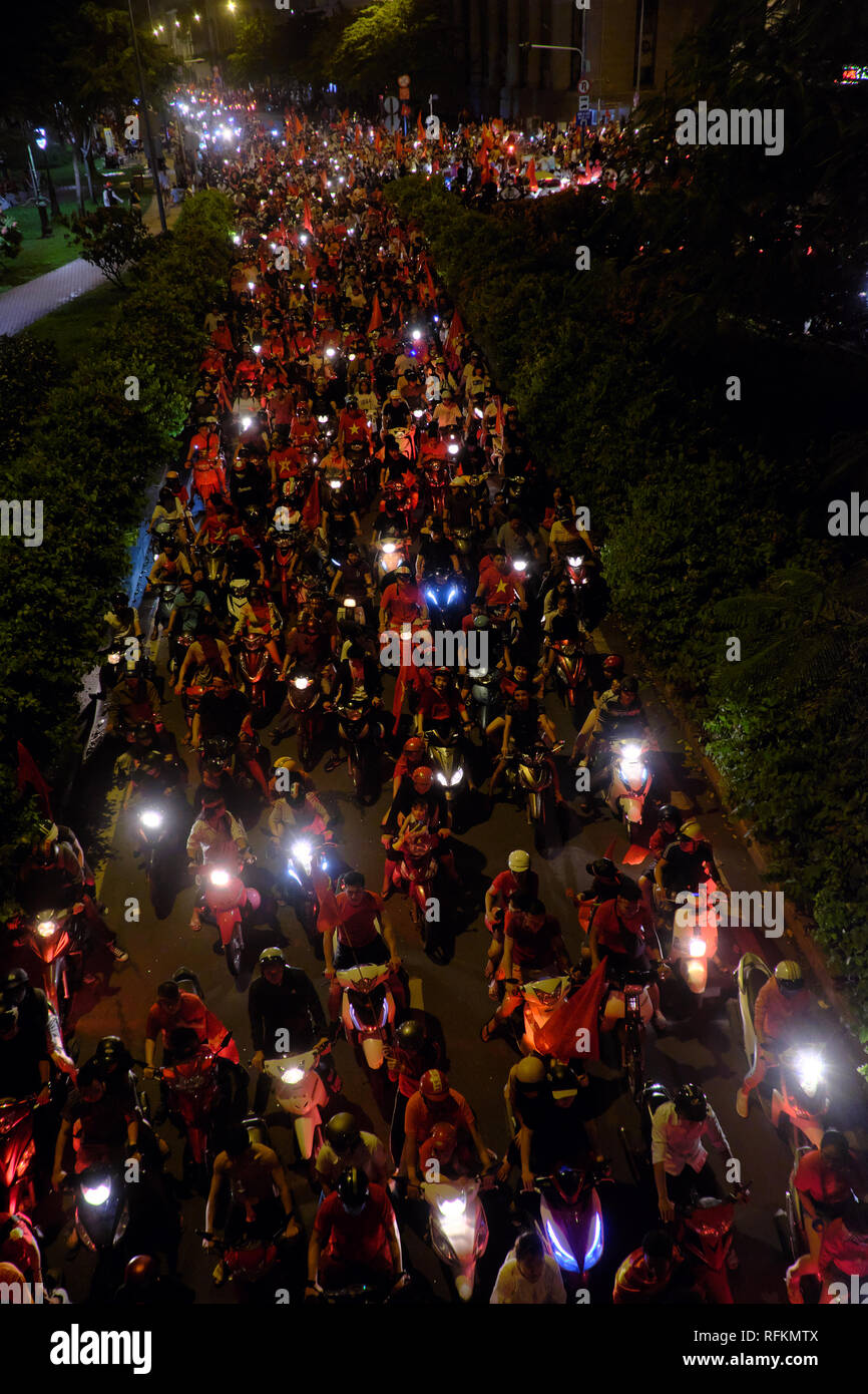 HO CHI MINH ville, VIET NAM, Groupe d'amateur de football en bas de la route pour la célébration, de nombreuses personnes ride moto avec drapeau rouge rendre la circulation Banque D'Images