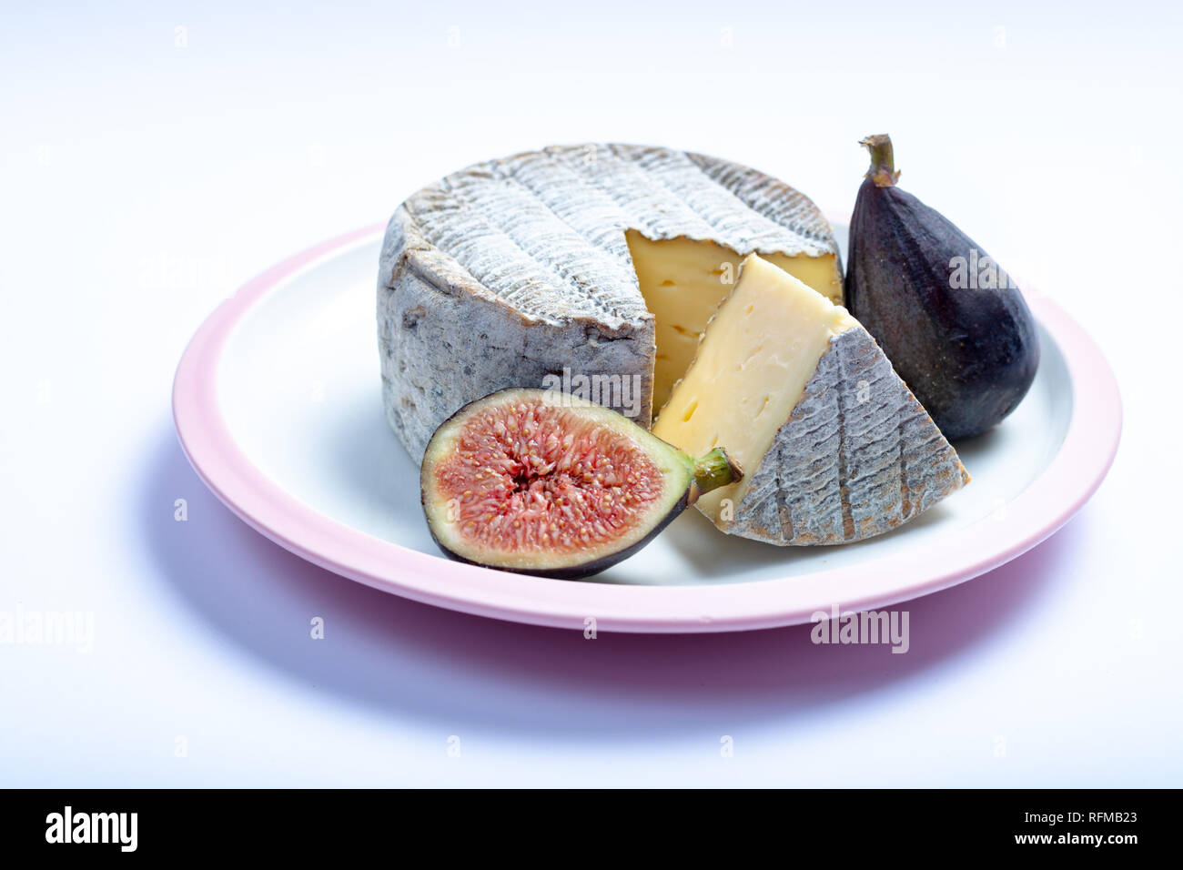 Mature ronde Tomme française avec un morceau coupé et figues mûres fraîches  isolées sur tableau blanc close up Photo Stock - Alamy