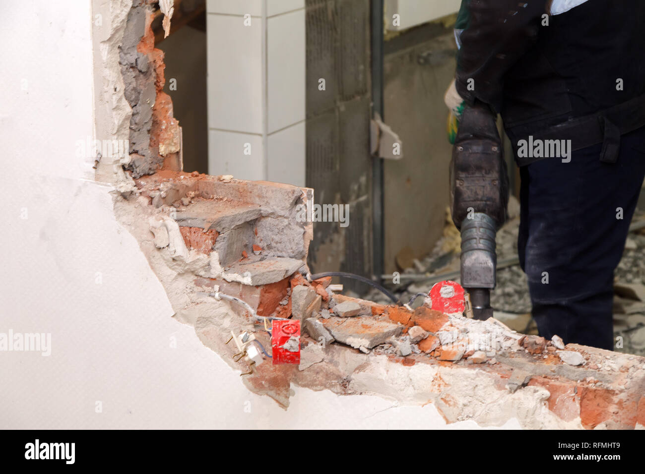 L'homme travailleur professionnel en uniforme poussiéreux casse brique, murs de béton et le carrelage avec perforateur. Révision du concept, la rénovation, le réaménagement de l'wal Banque D'Images