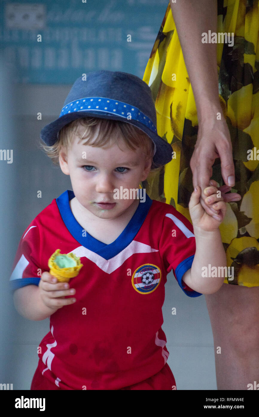 Aa portrait d'une jeune équipe de football du Costa Rica visite d'un ventilateur de jeu avec sa mère. Le garçon est d'avoir une glace pistache. Banque D'Images