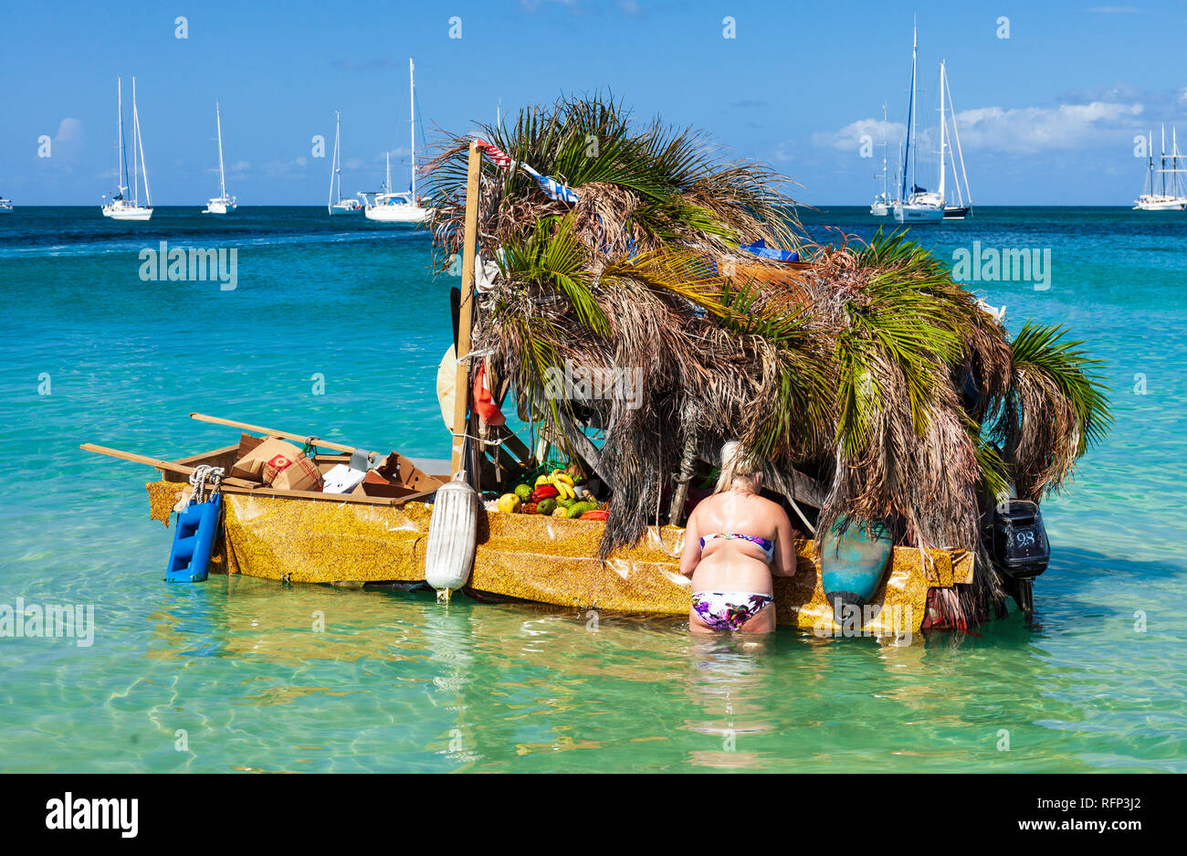 Femme faisant un achat dans un magasin de fruits flottants shanty bateau, plage de Reduit Rodney Bay, Sainte-Lucie, Caraïbes. Banque D'Images