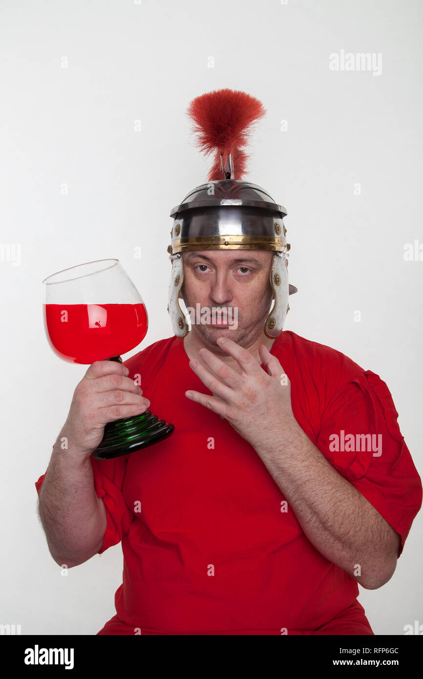 Un soldat romain ivre avec un verre de vin sur le fond blanc. Banque D'Images