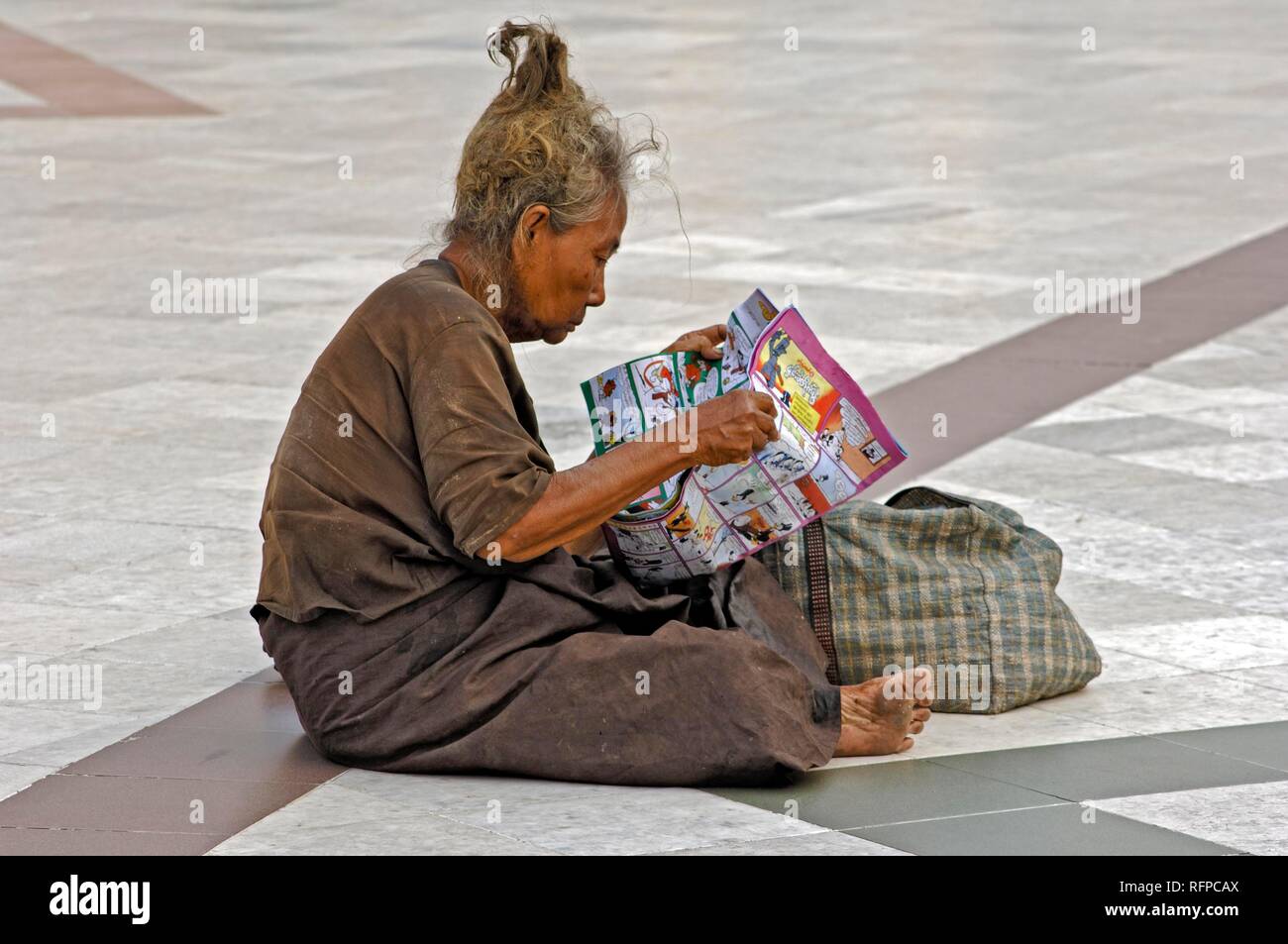 Vieille Femme à la lecture d'un dessin animé, de la pagode Shwedagon, Yangoon, Myanmar, Birmanie, Rangun Banque D'Images