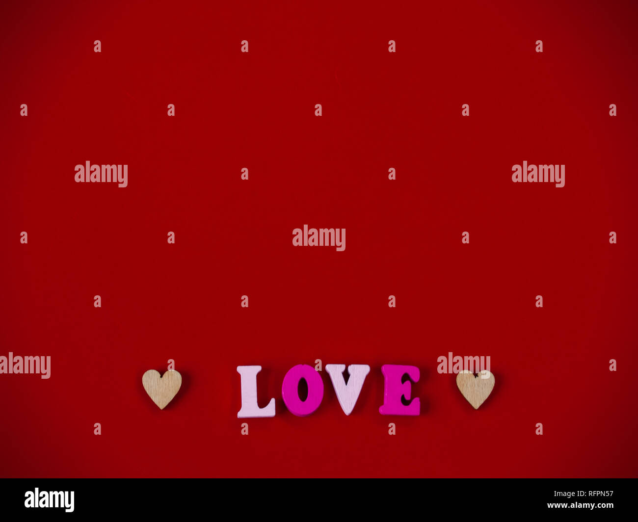 Concept d'amour Le mot amour dans des lettres en bois et les coeurs avec un fond rouge Banque D'Images