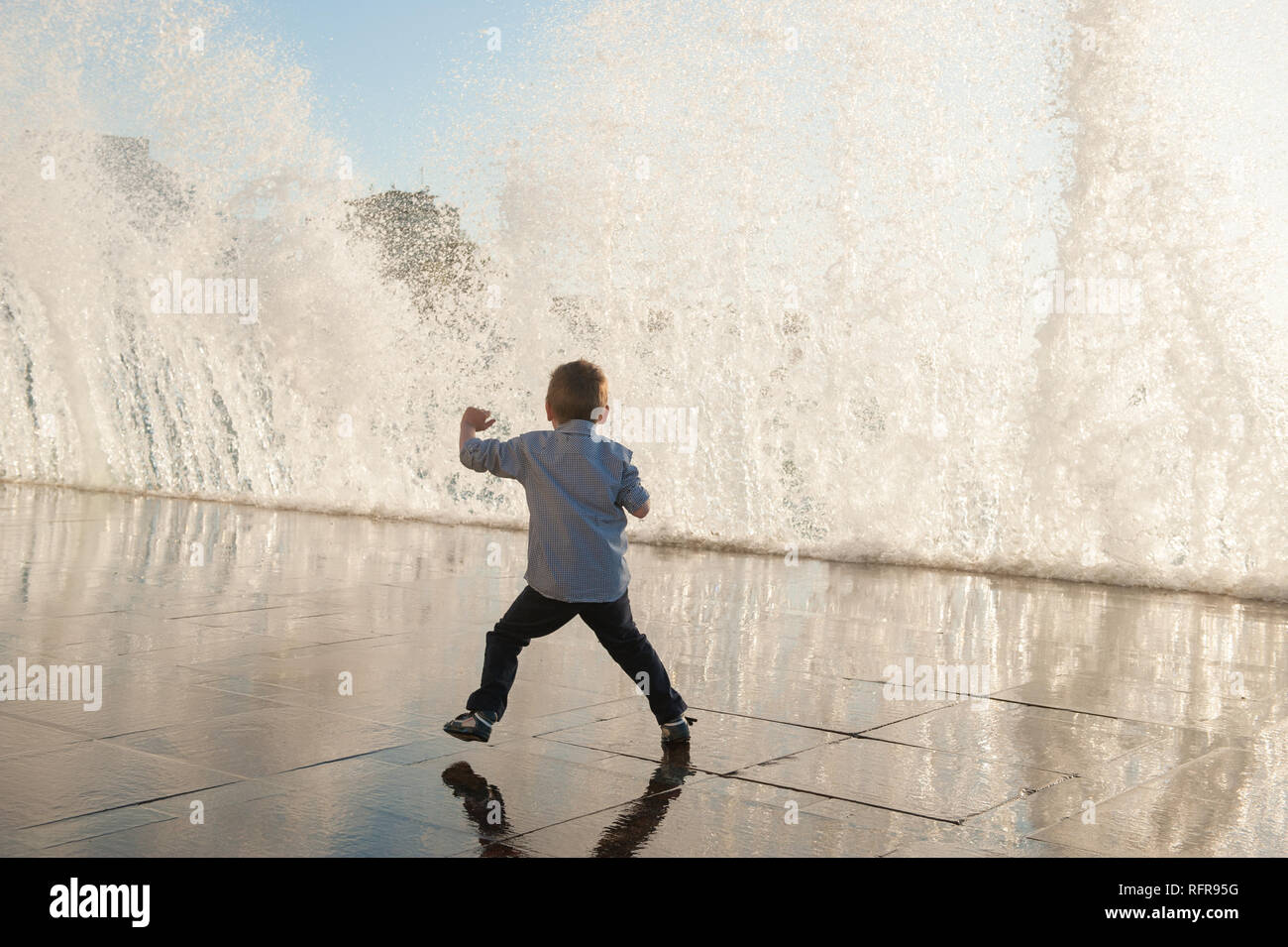 Un petit enfant s'échapper frome énorme vague sur la mer en ville pendant le temps de tempête Banque D'Images