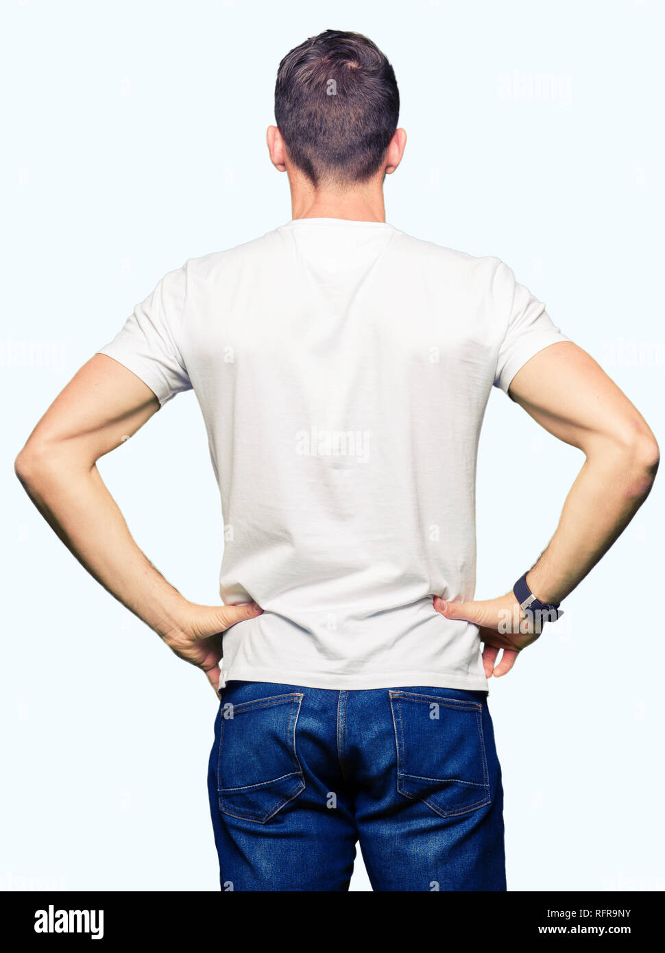 Bel homme portant un t-shirt blanc à l'arrière debout à l'écart avec les bras sur le corps Banque D'Images