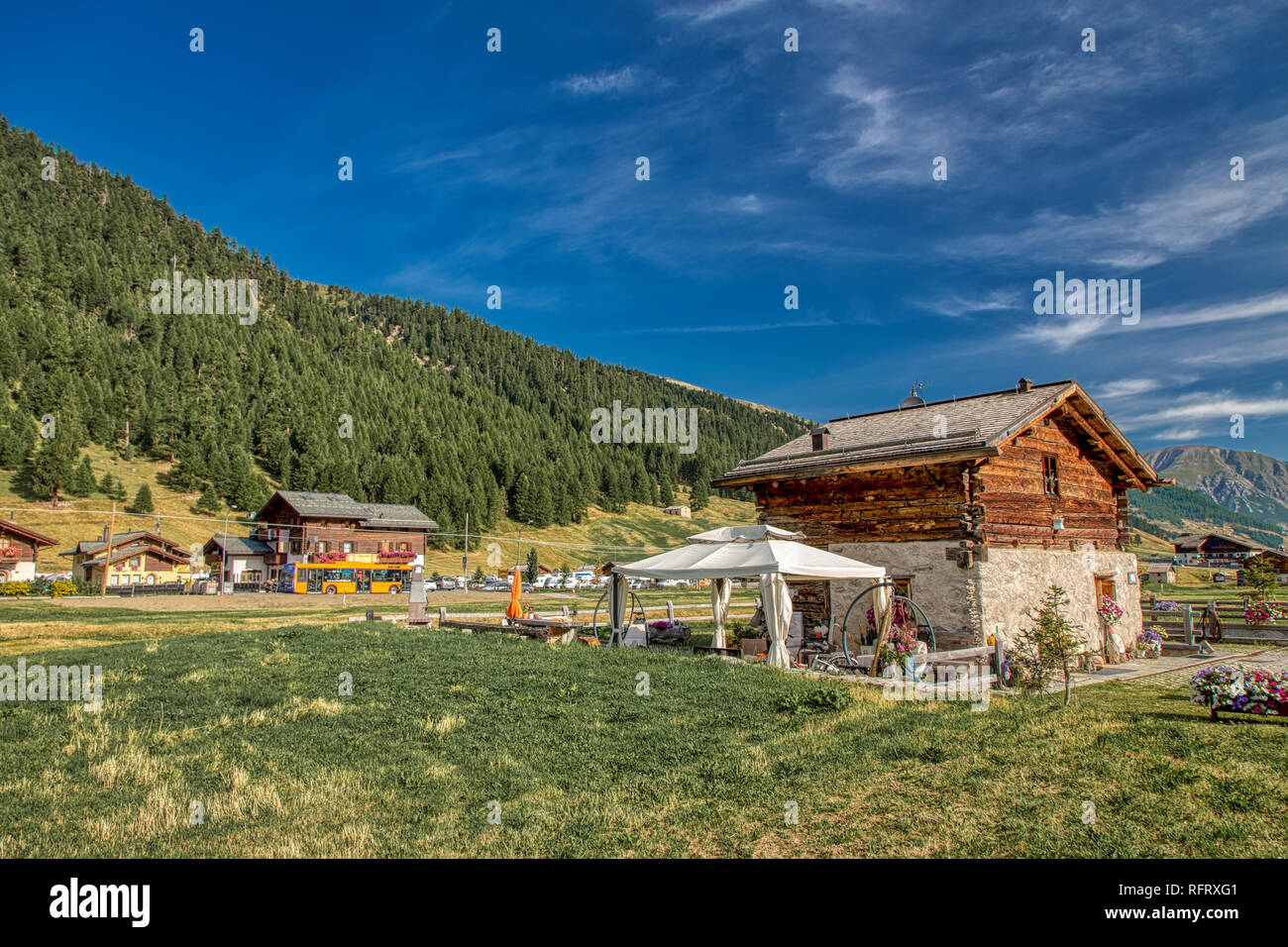 Scenic alpine valley à Livigno, Italie avec un traditionnel de bois et de pierre nichée entre les sommets de montagnes boisées Banque D'Images