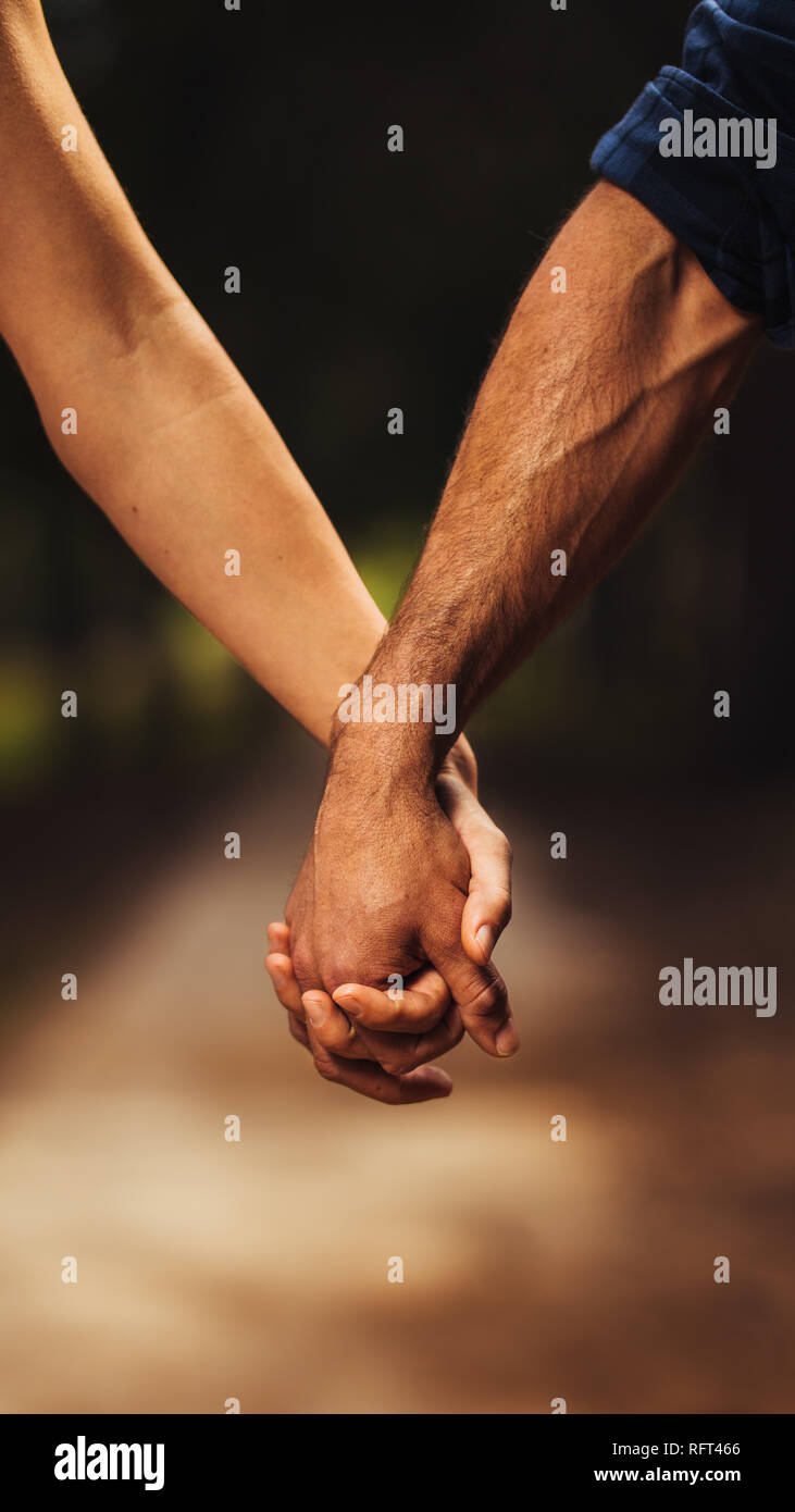 Close up of loving couple holding hands dans le parc. Cropped shot of romantic couple avec la main dans la main sur la nature. Banque D'Images