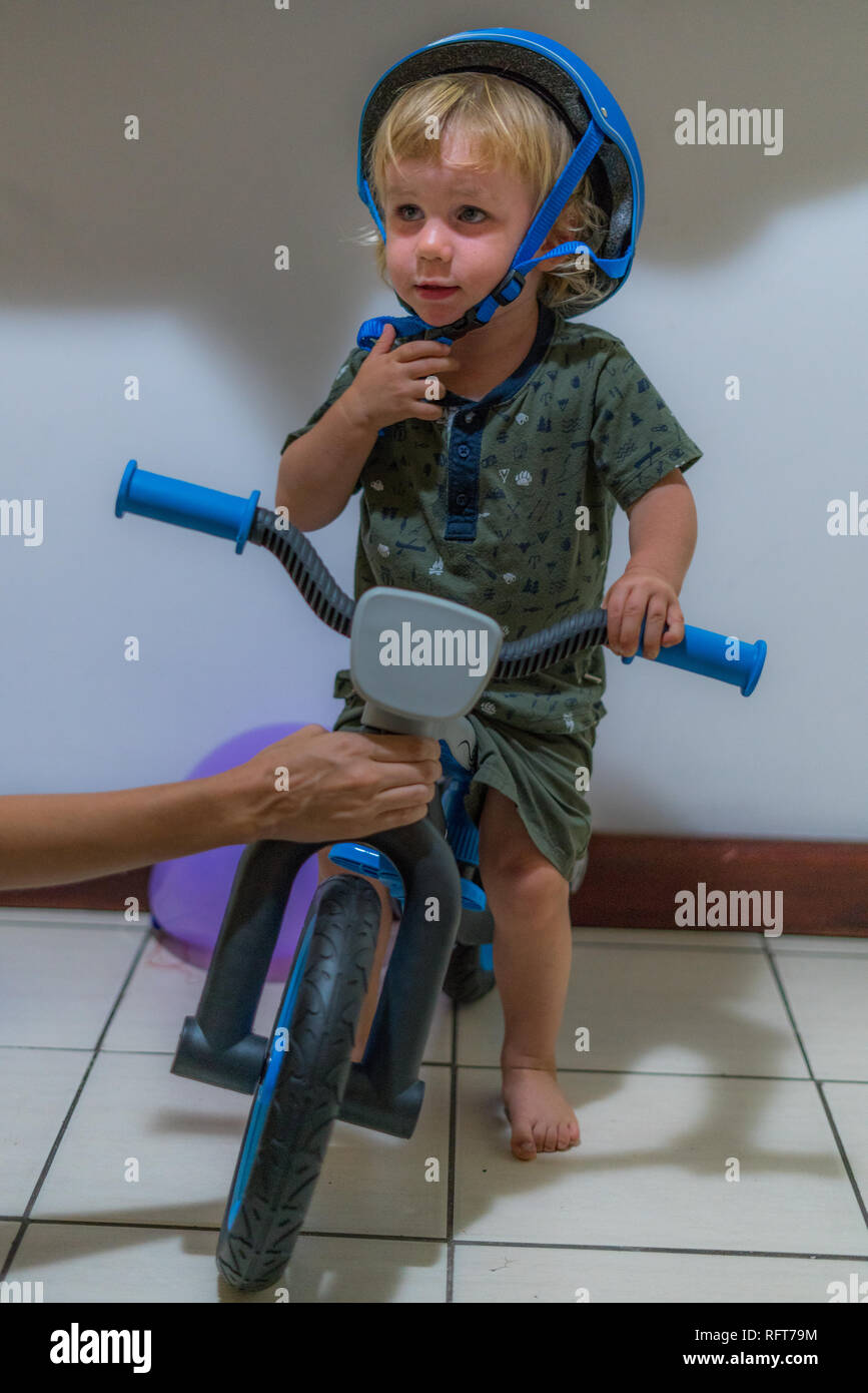Un portrait d'un joyeux anniversaire garçon après avoir reçu son premier vélo. Le garçon porte un casque bleu. Banque D'Images