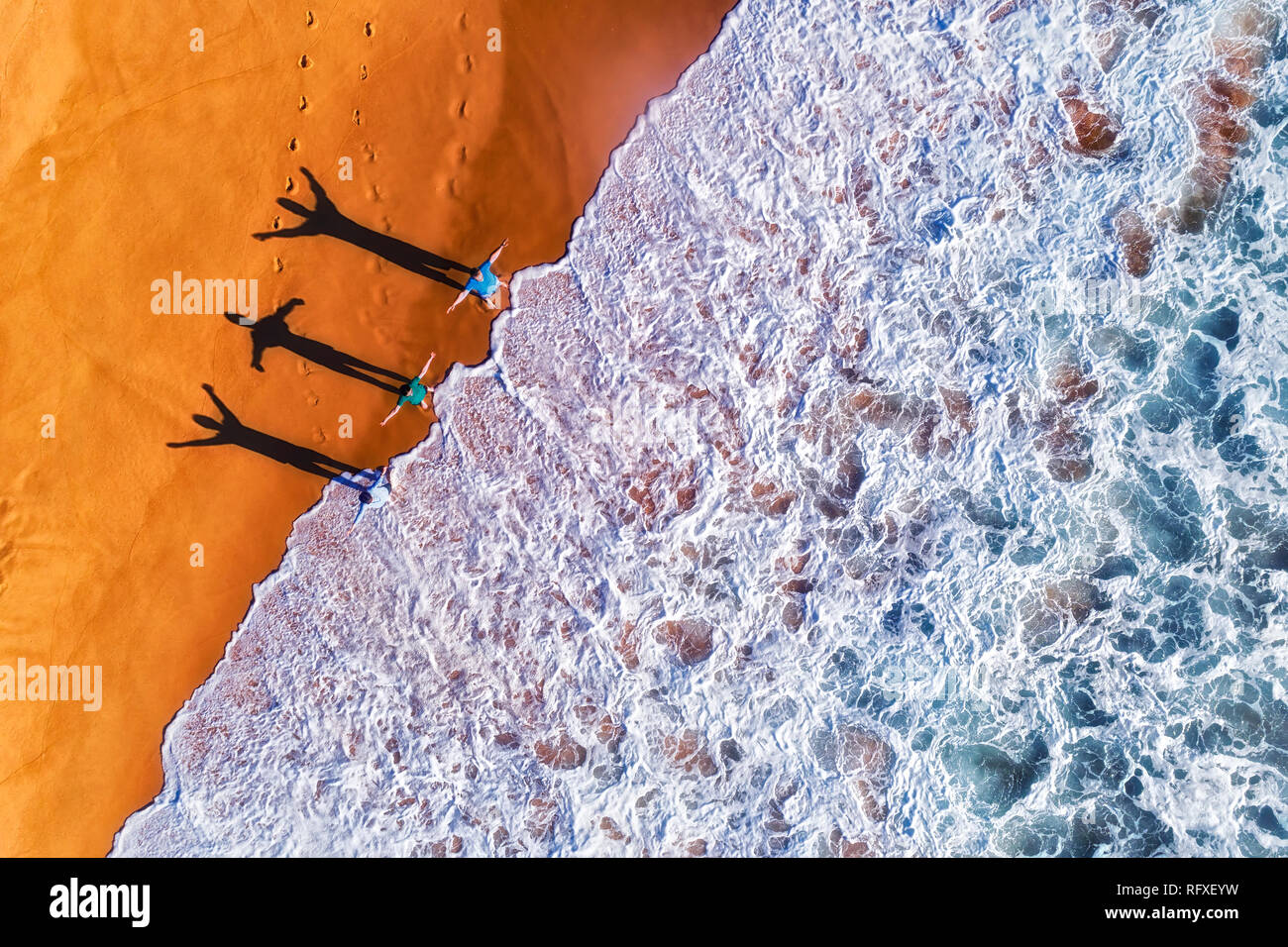 Trois personnes de l'exercice actif face à des vagues de surf de l'océan Pacifique sur la plage de sable isolée plages du nord de Sydney dans la chaleur du soleil lig Banque D'Images