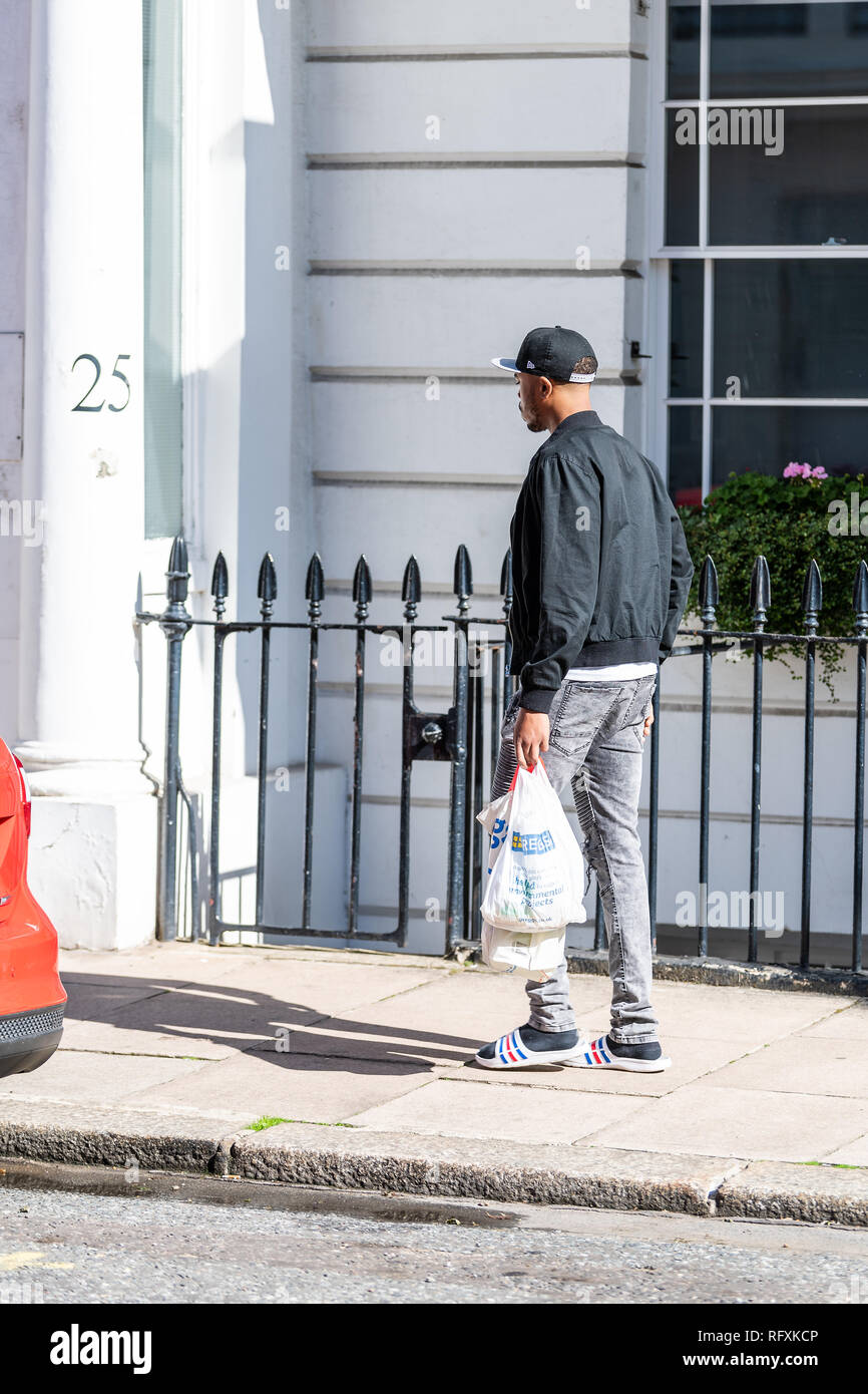 Londres, Royaume-Uni - 13 septembre 2018 : Pimlico salon avec des bâtiments et de l'homme exerçant la marche à pied les sacs d'épicerie sur le pavé de Greggs cafe store Banque D'Images