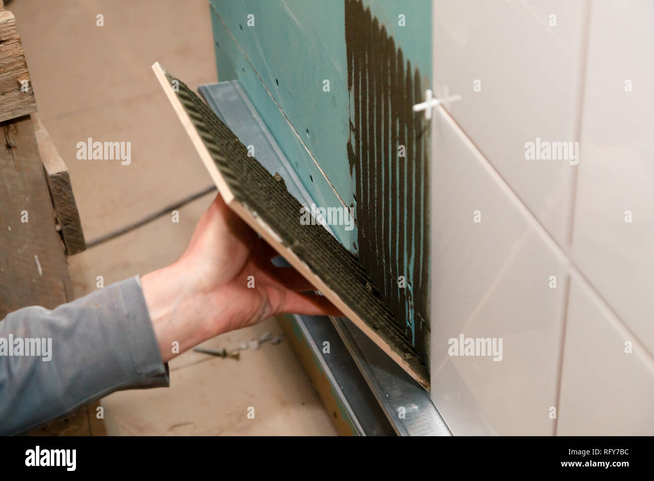 Libre constructeur professionnel de la main de l'homme de colles en carreaux de céramique avec de l'adhésif dans la salle de bains. Concept Rénovation Réparation, révision, carreleur, contrat de l'équipe Banque D'Images