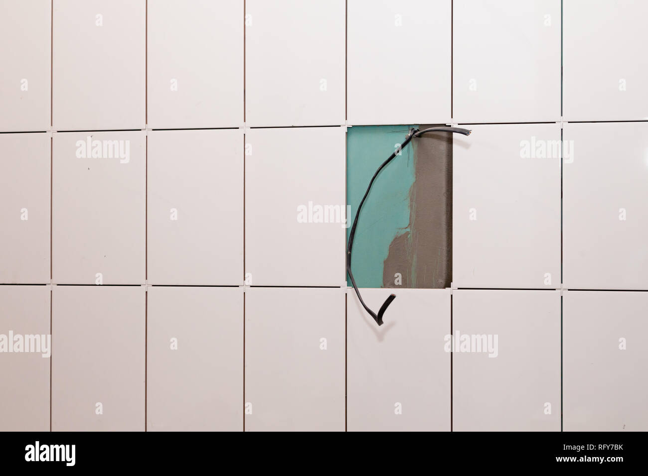 Carrelage blanc Gros plan sur le mur de gypse sans coulis et câbles électriques. La notion de réparation dans la salle de bains, toilettes, cuisine, câblage, installation Banque D'Images