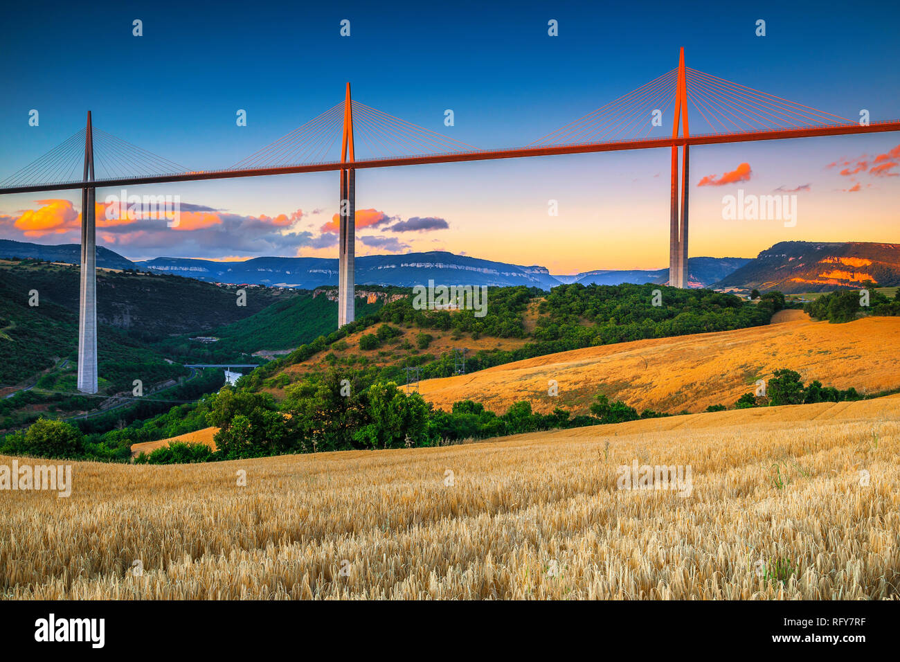 Situation touristique et architectural étonnant. Admirable viaduc de Millau et des champs de céréales au coucher du soleil, Aveyron, France, Europe Banque D'Images