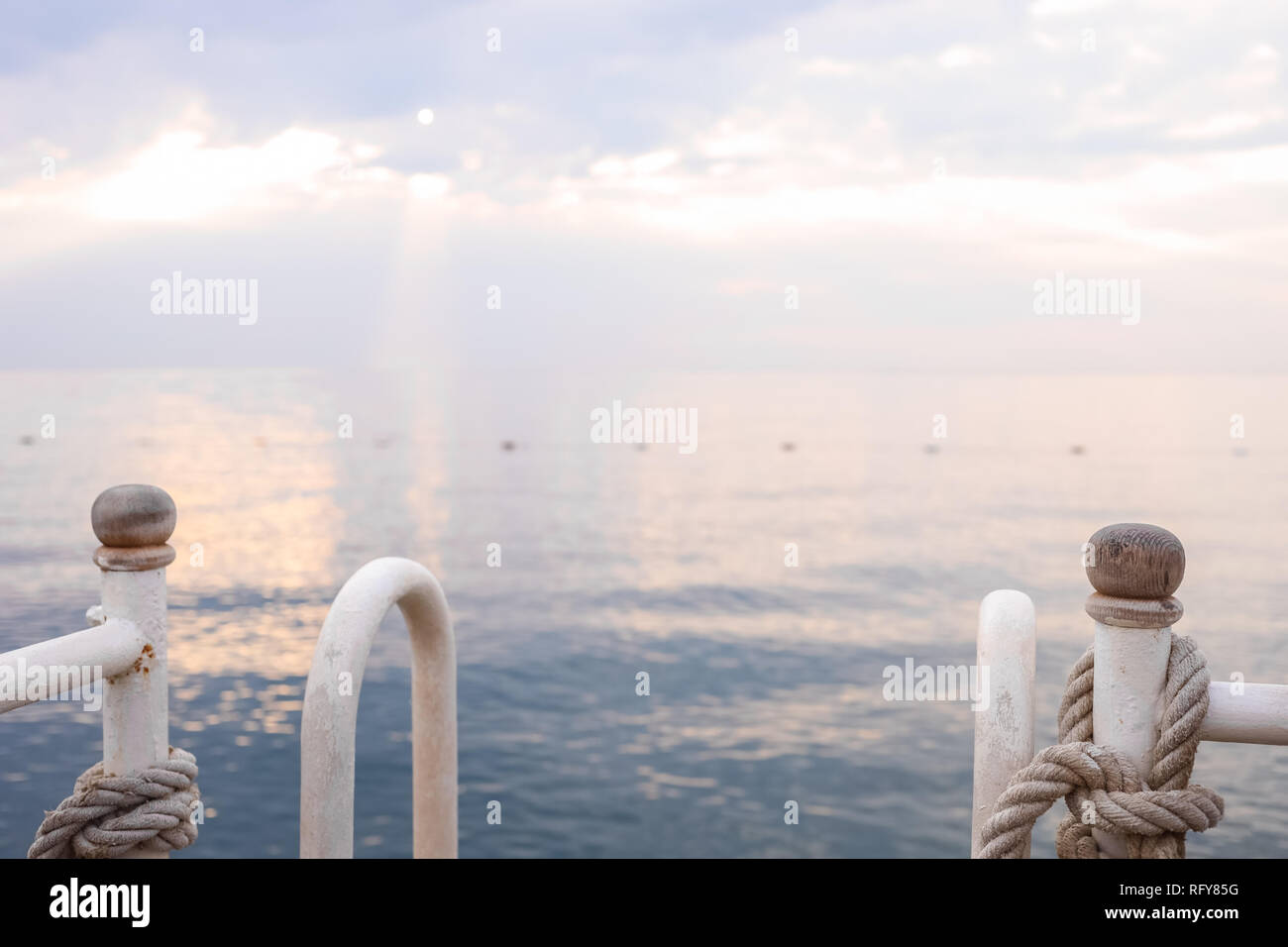 Seascape sur le lever du soleil et garde-corps en métal avec des cordes en premier plan. Banque D'Images