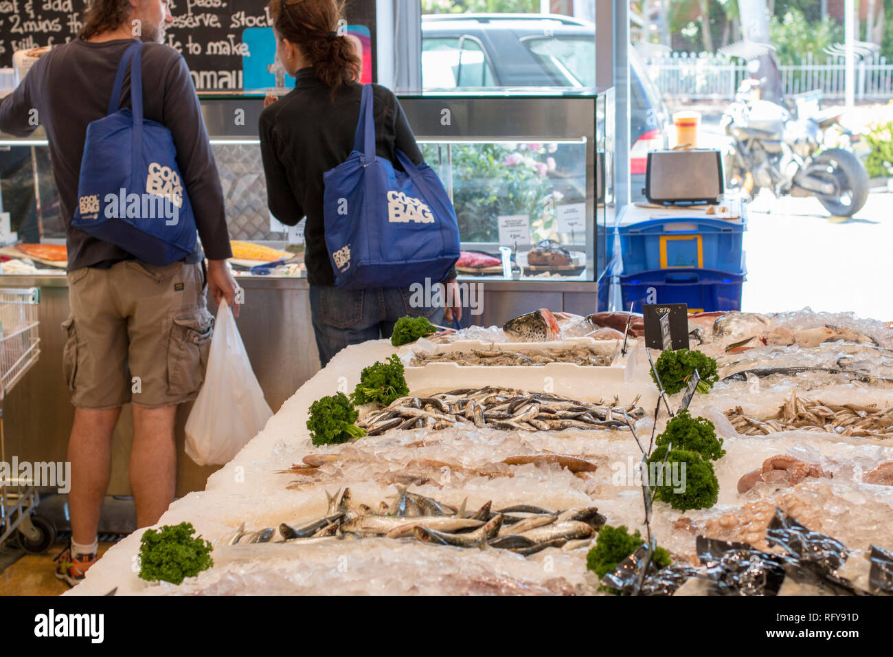 Poissonniers magasin à Sydney Manly Beach, Sydney, Australie, couple carrying sacs isothermes pour stocker le poisson dans Banque D'Images