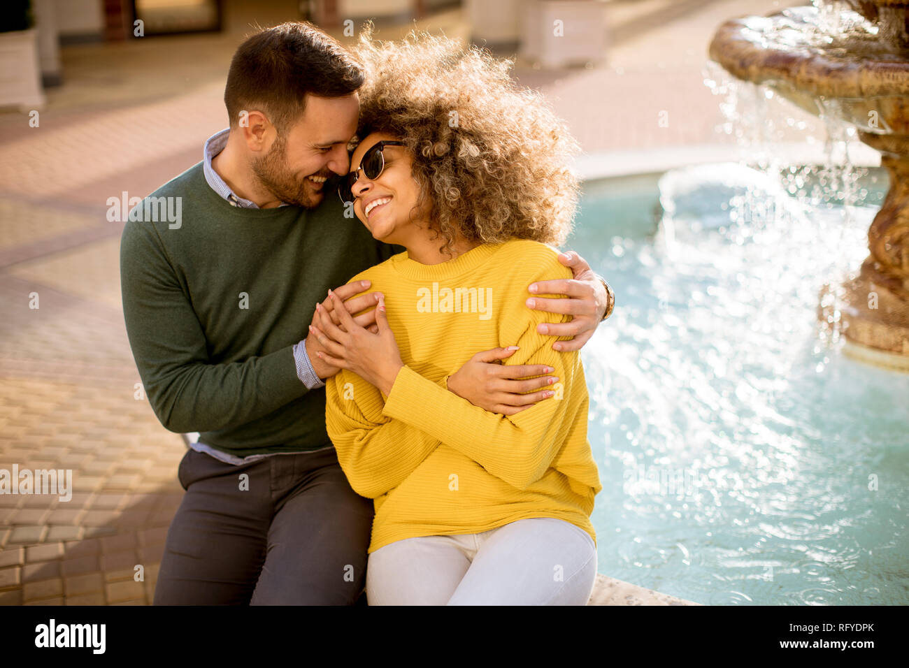 Portrait of beautiful smiling love couple assis près de la fontaine, un jour ensoleillé Banque D'Images