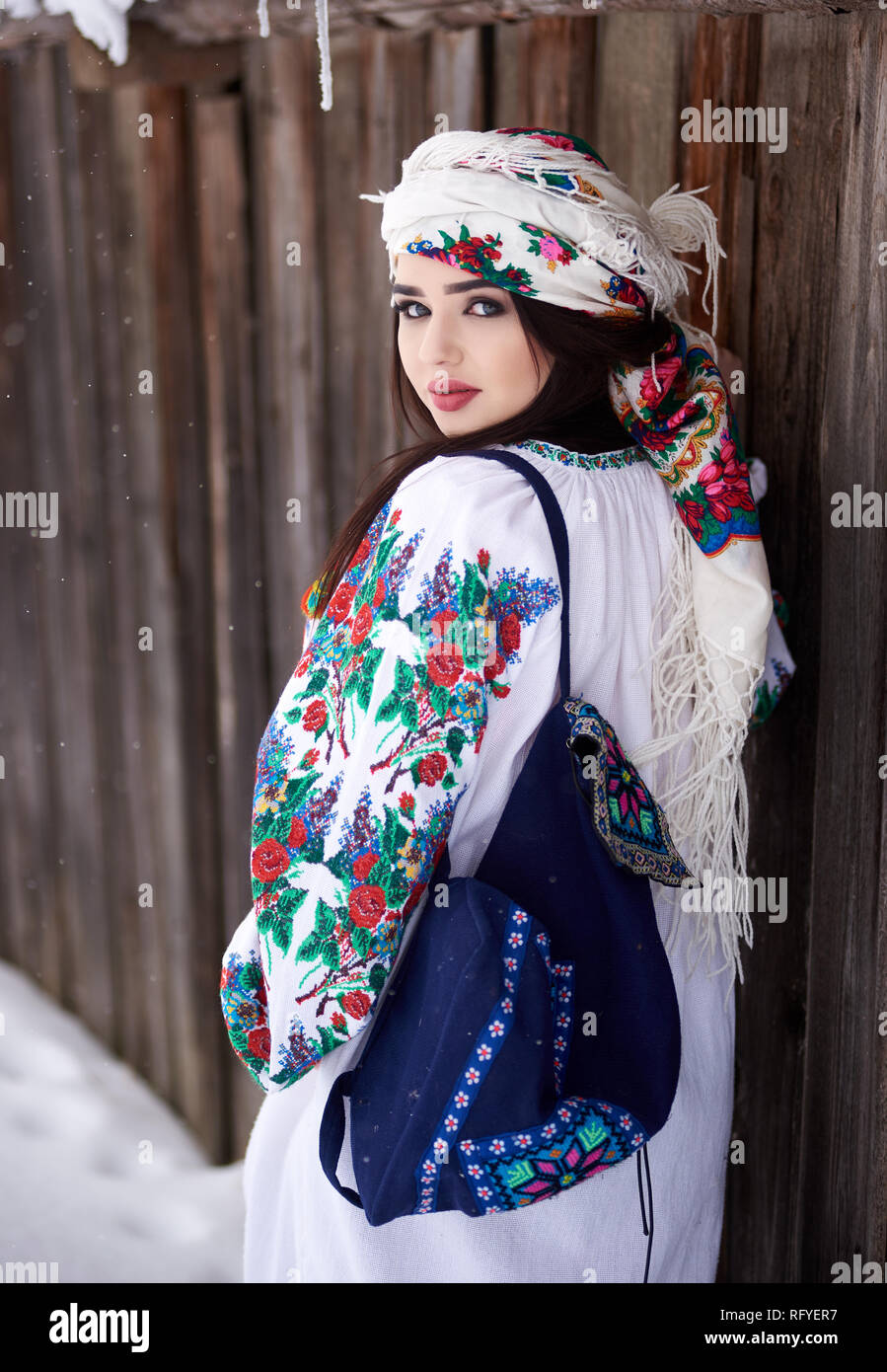 Vue arrière de la jeune fille brune en robe blanche, manches brodé de fleurs colorées, fichu et bleu , sac d'épaule Banque D'Images