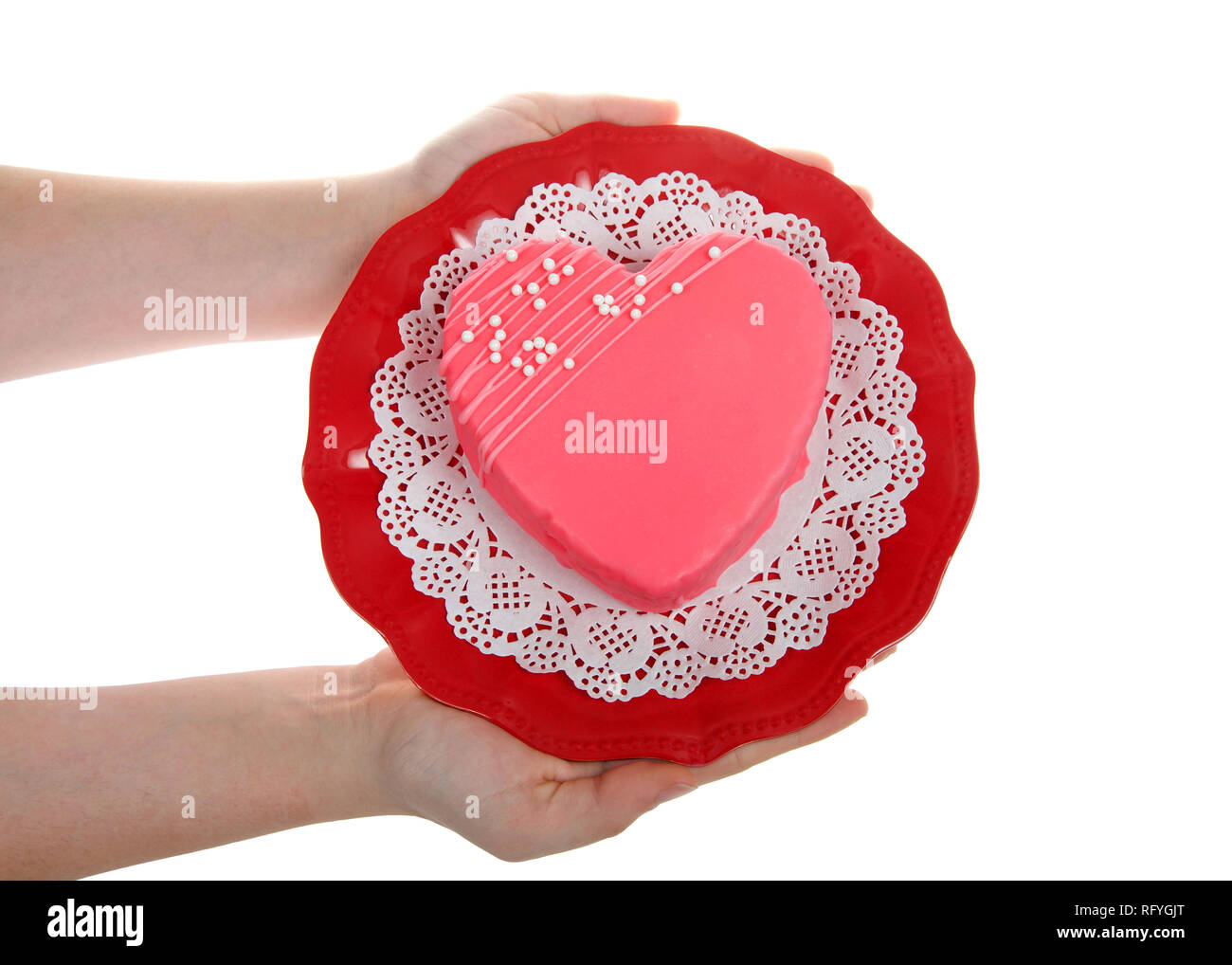 Jeune femme mains tenant la plaque rouge scaloped avec doilie blanc en forme de coeur rose avec des bonbons gâteau sur sprinkles haut isolé sur fond blanc. Valen Banque D'Images