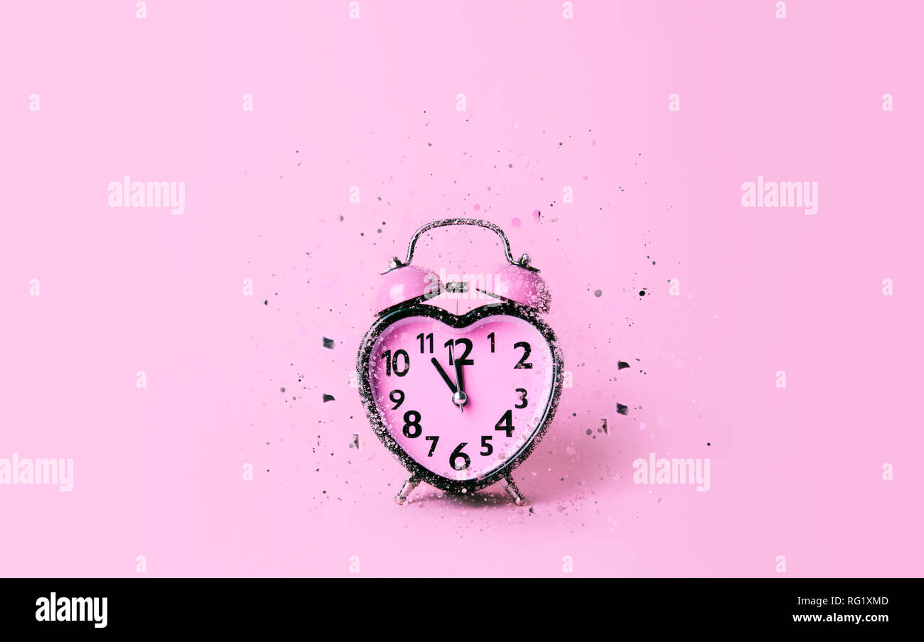 Horloge en forme de coeur sur fond rose. Banque D'Images