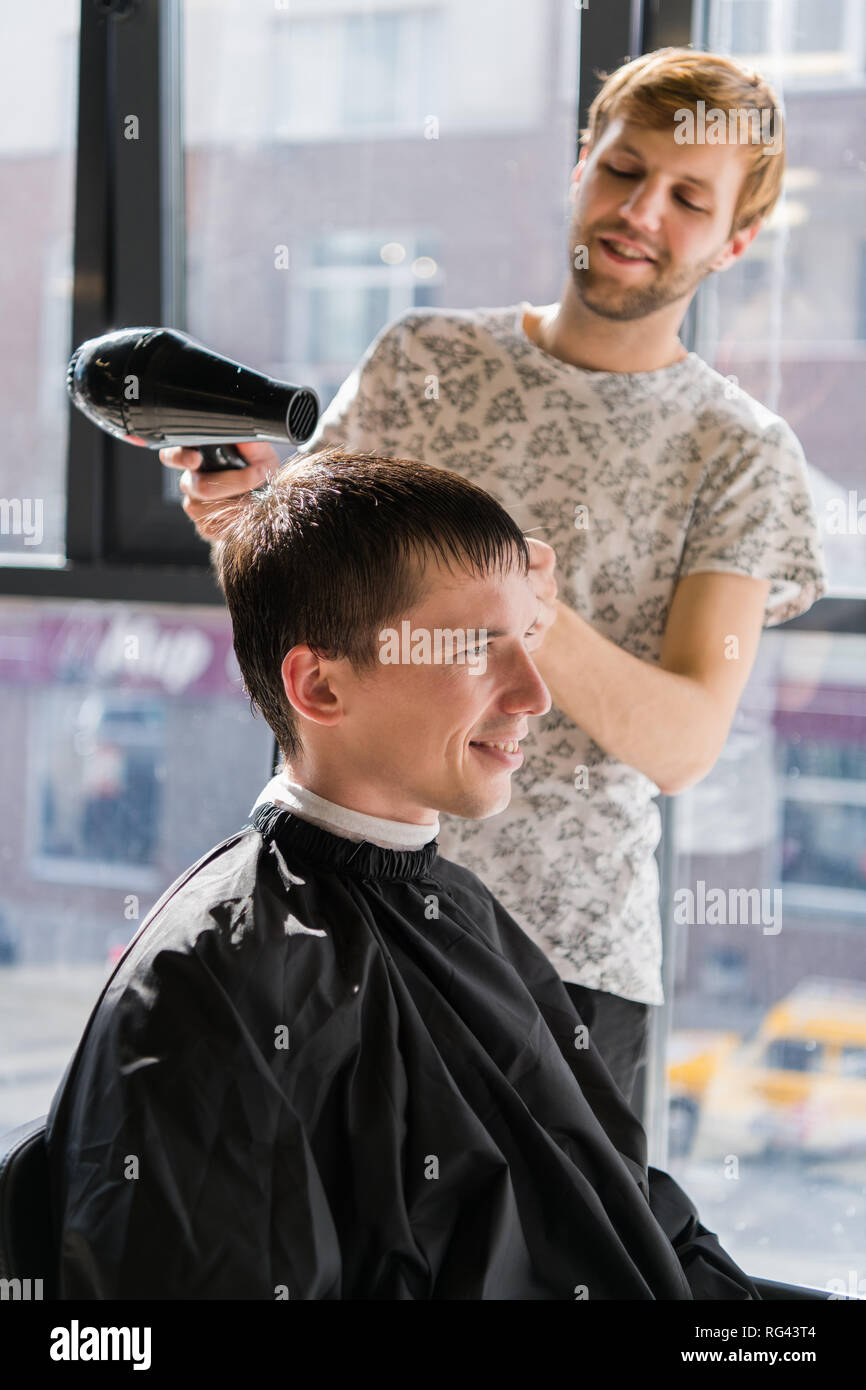 Jeune hipster guy dans un salon de coiffure, coiffure la coupe de cheveux avec des ciseaux, le séchage. Les hommes concept place Banque D'Images