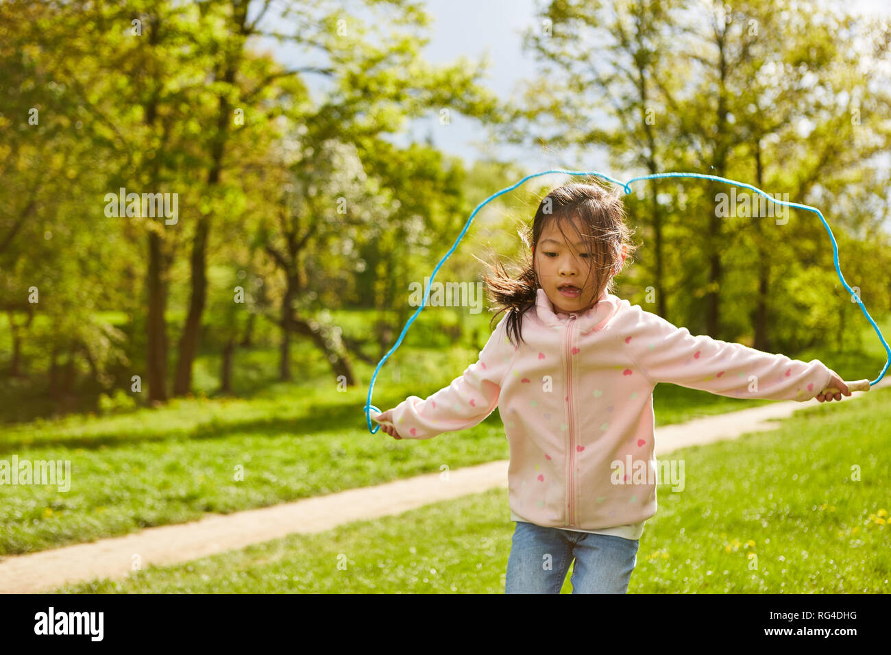 L'enfant actif saute à la corde à sauter dans le parc à l'été pendant les vacances Banque D'Images