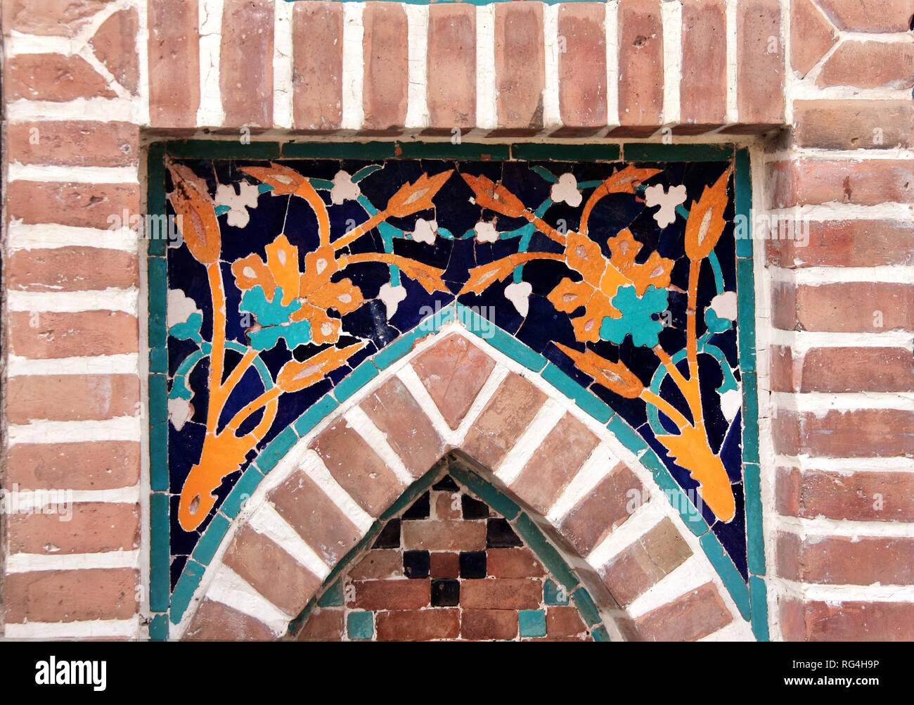 Détail de l'ancien mur de mosaïque avec motif floral géorgien traditionnel de couleurs jaune et bleu dans le cadre de la brique Banque D'Images