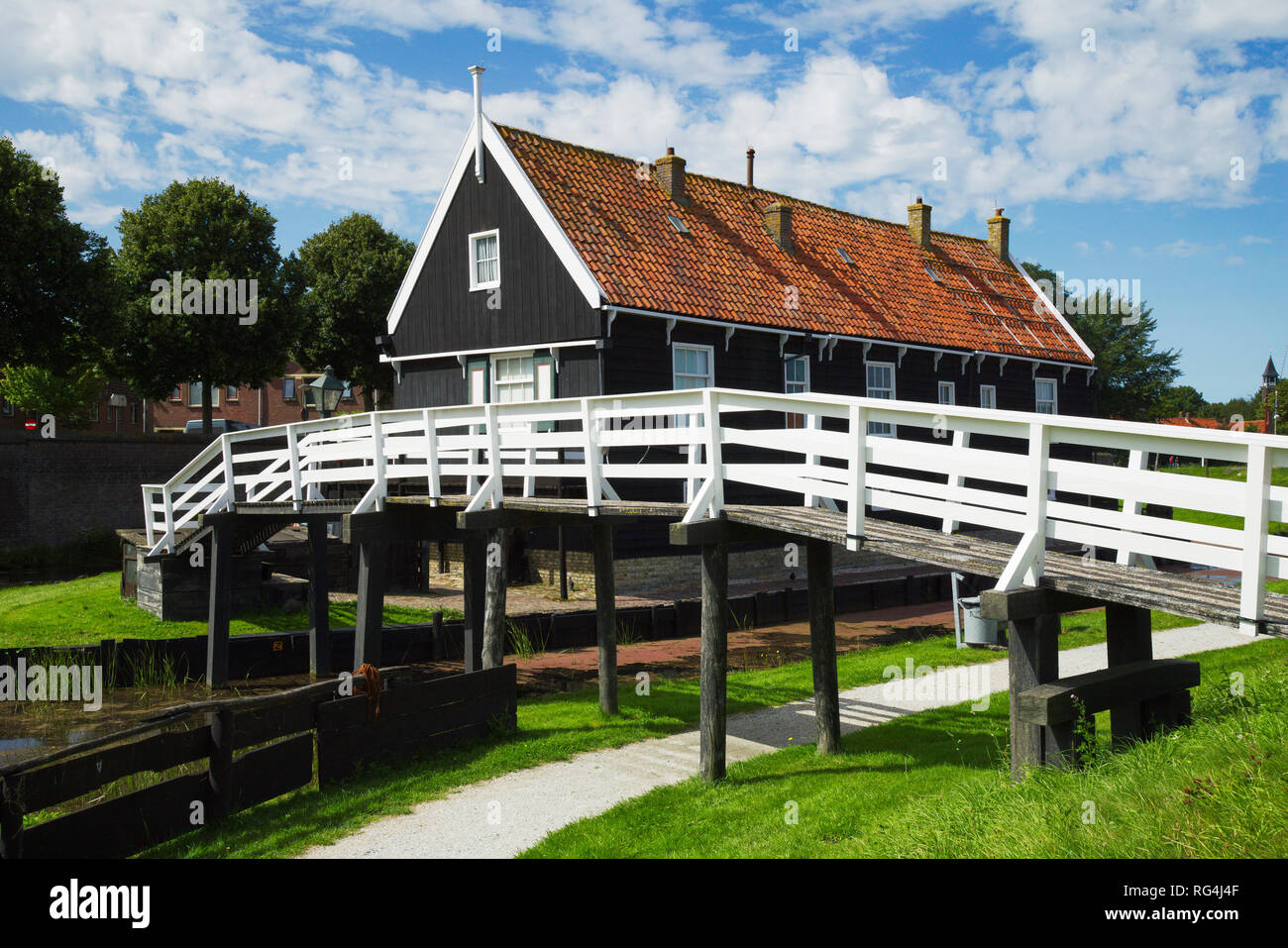 Maison de pêcheur traditionnelle avec pont de bois blanc, d'arbres et l'herbe, des nuages et ciel bleu à Enkhuizen, petite ville en Pays-Bas. Banque D'Images