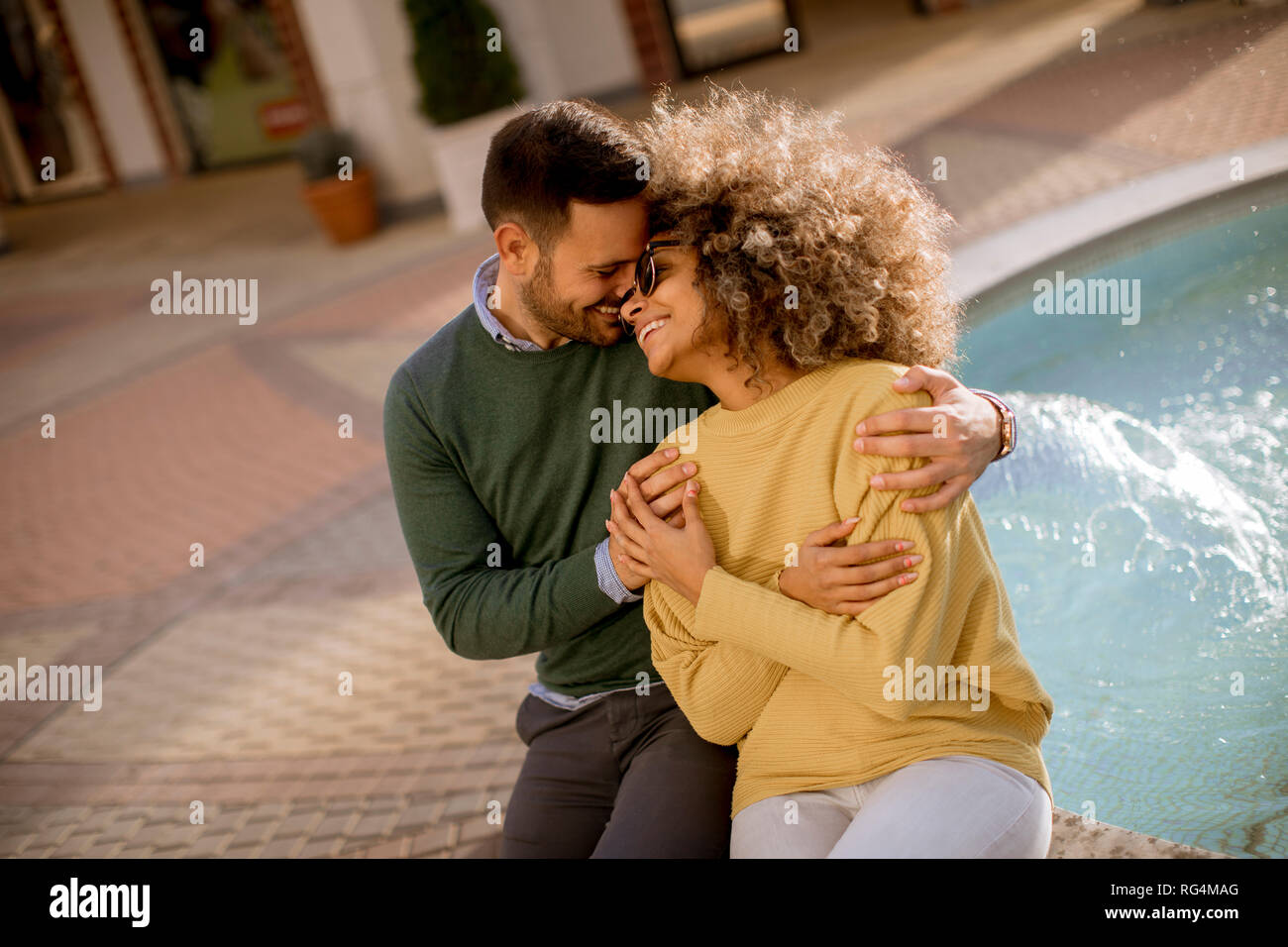 Portrait of beautiful smiling love couple assis près de la fontaine, un jour ensoleillé Banque D'Images