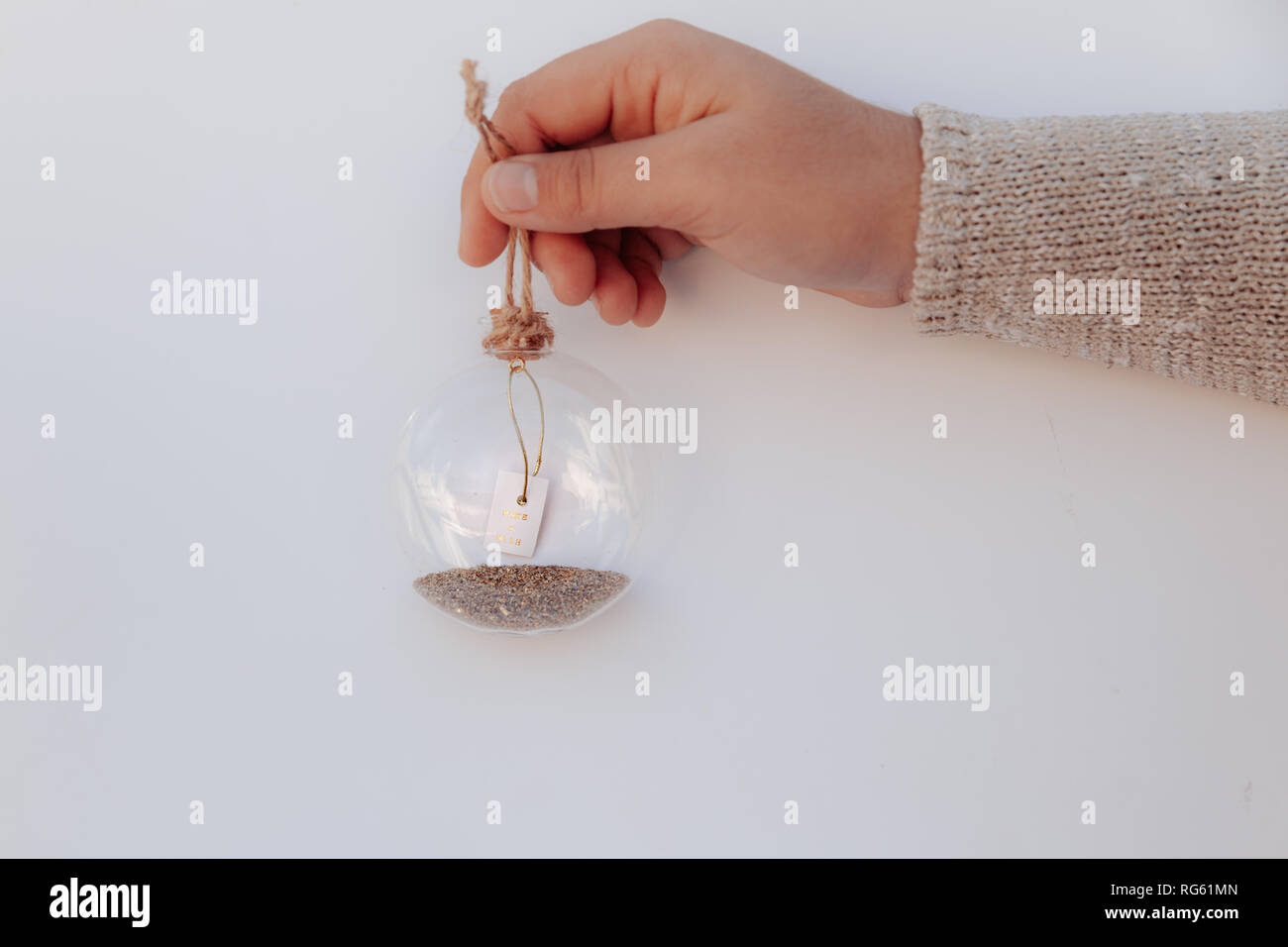 Girl's hand holding a glass bauble avec un message make a wish Banque D'Images