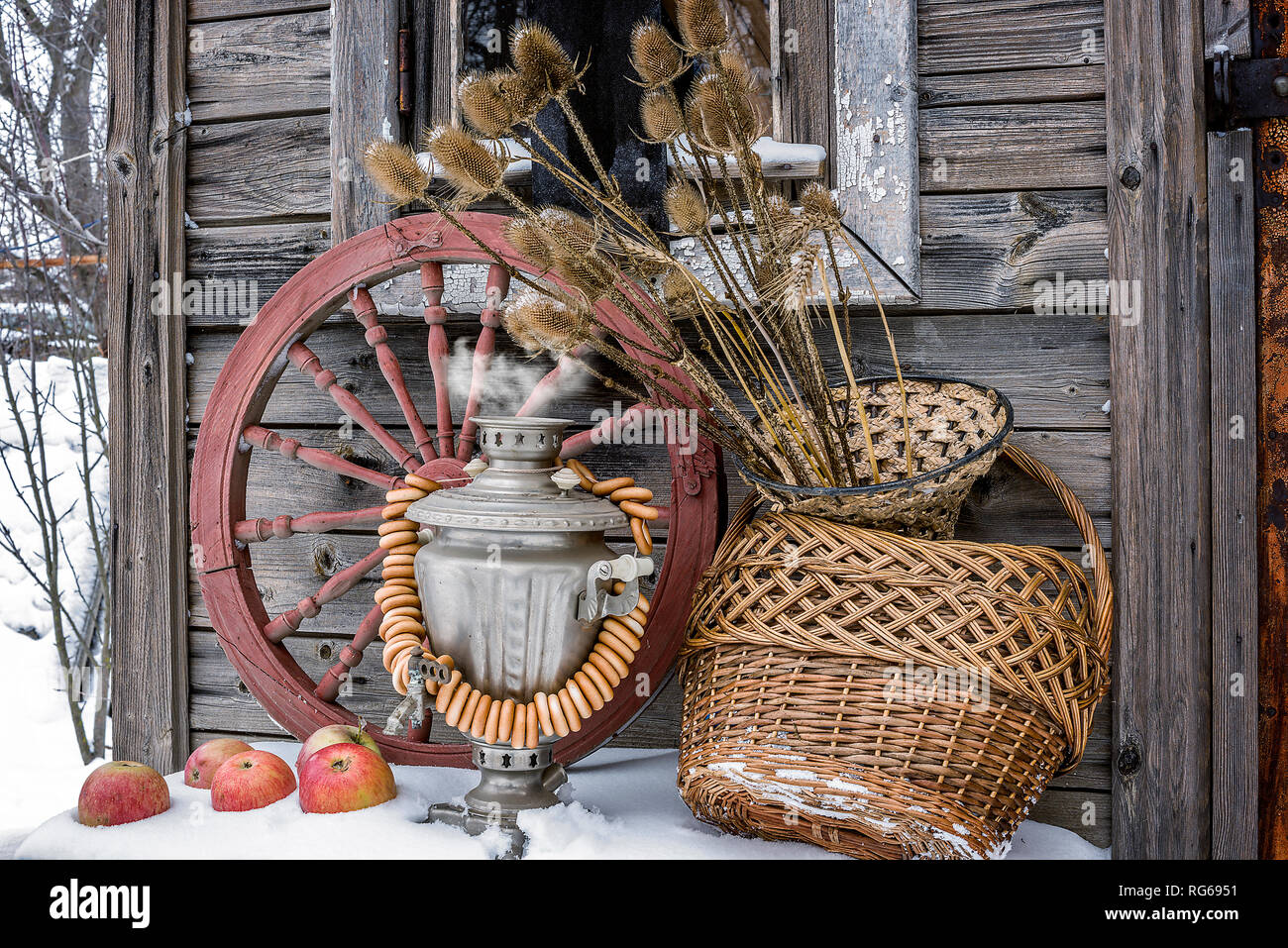 La vie encore rural. Sex samovar, direction-roues, pommes sur la neige, de la roue tournante, willow panier de paille, avec des pots de plantes sèches dans un contexte o Banque D'Images