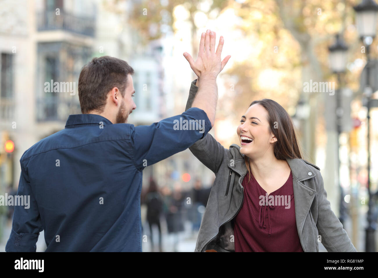 Deux excités amis ou couple giving high five in a city street Banque D'Images