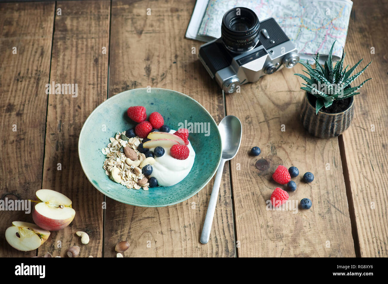 Bol de petit-déjeuner avec des céréales, yaourts, noix, pomme, framboise, myrtille sur bois Banque D'Images